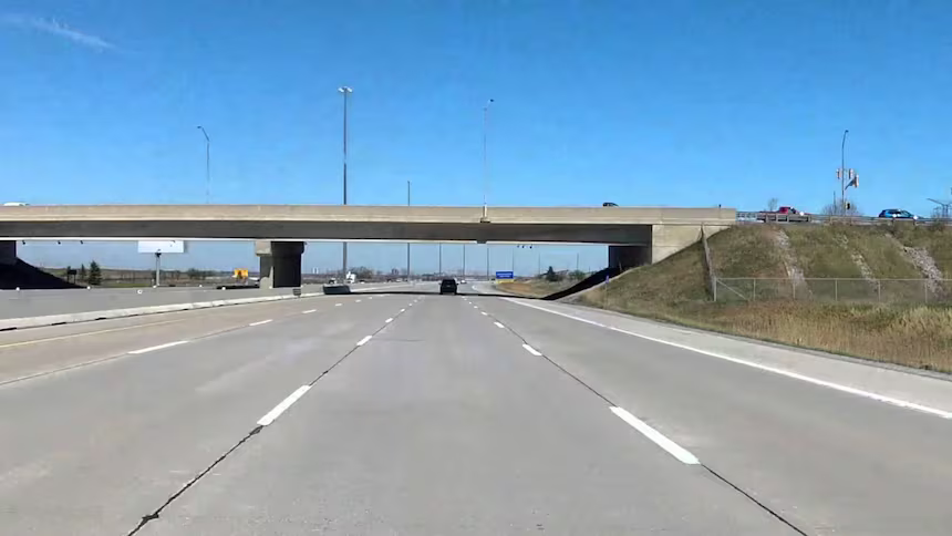 Empty highway with overpass bridge and clear blue sky