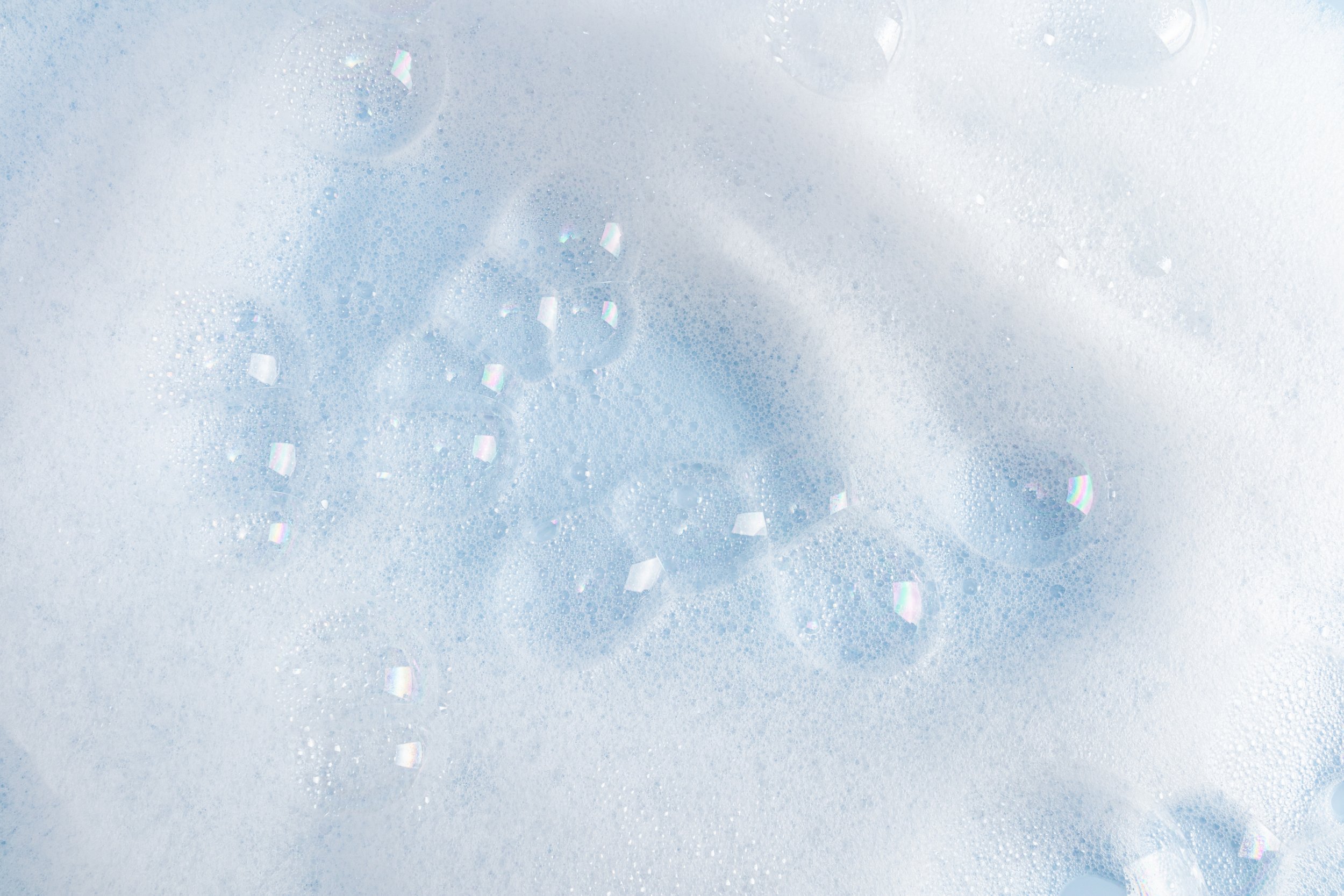 Close-up of soap bubbles and foam with iridescent reflections.