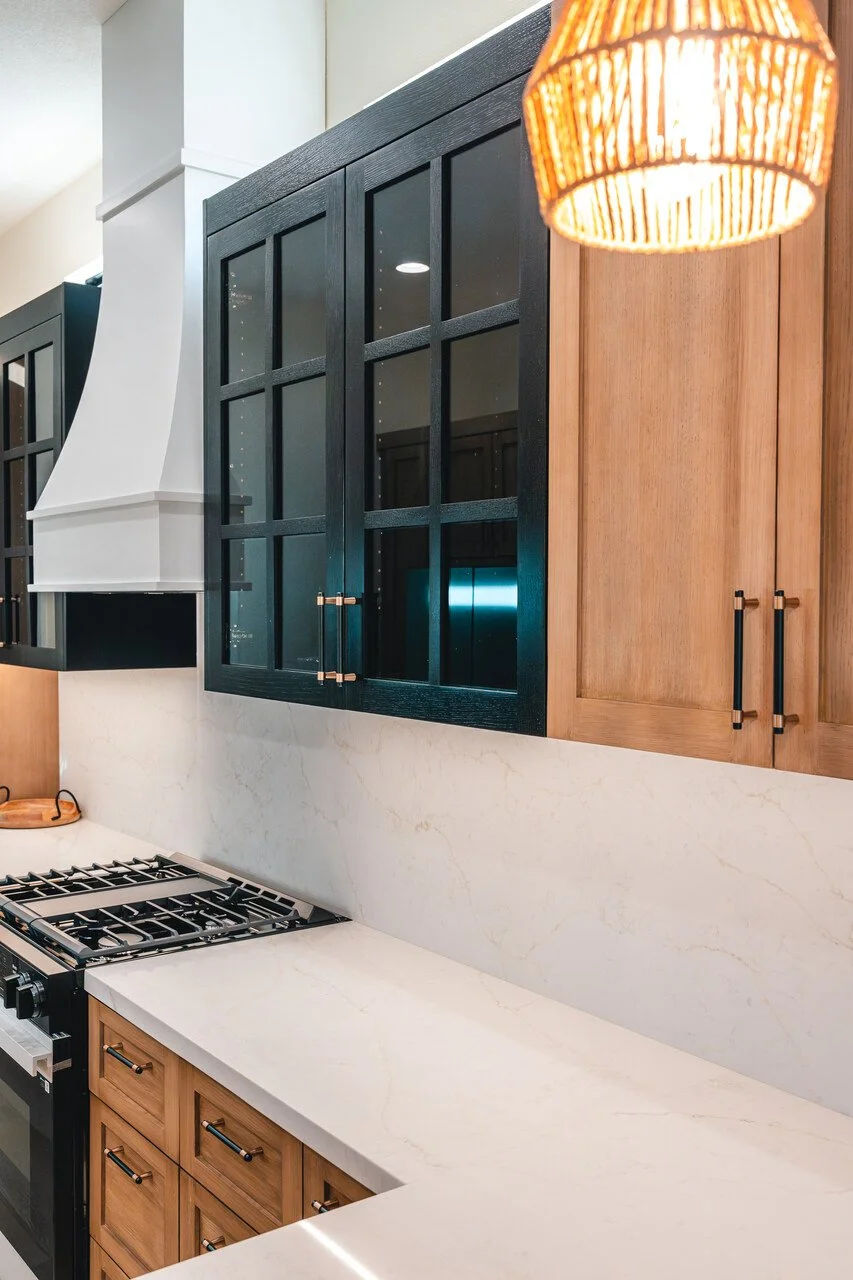 Modern kitchen with wooden and black cabinetry, white marble backsplash, and a black stovetop.