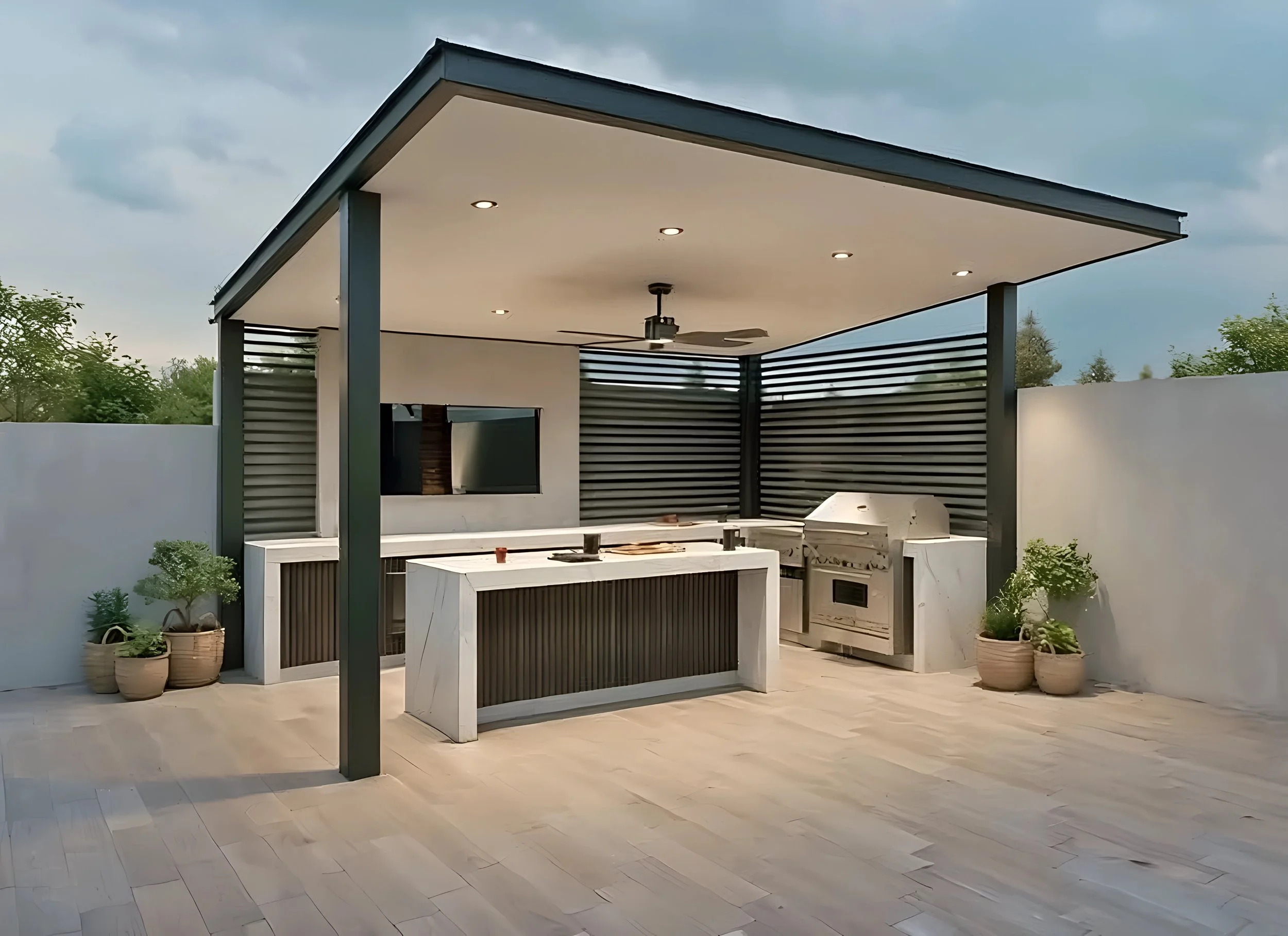 Modern outdoor kitchen with a covered roof, built-in grill, white island, and potted plants, set against a white wall and cloudy sky.