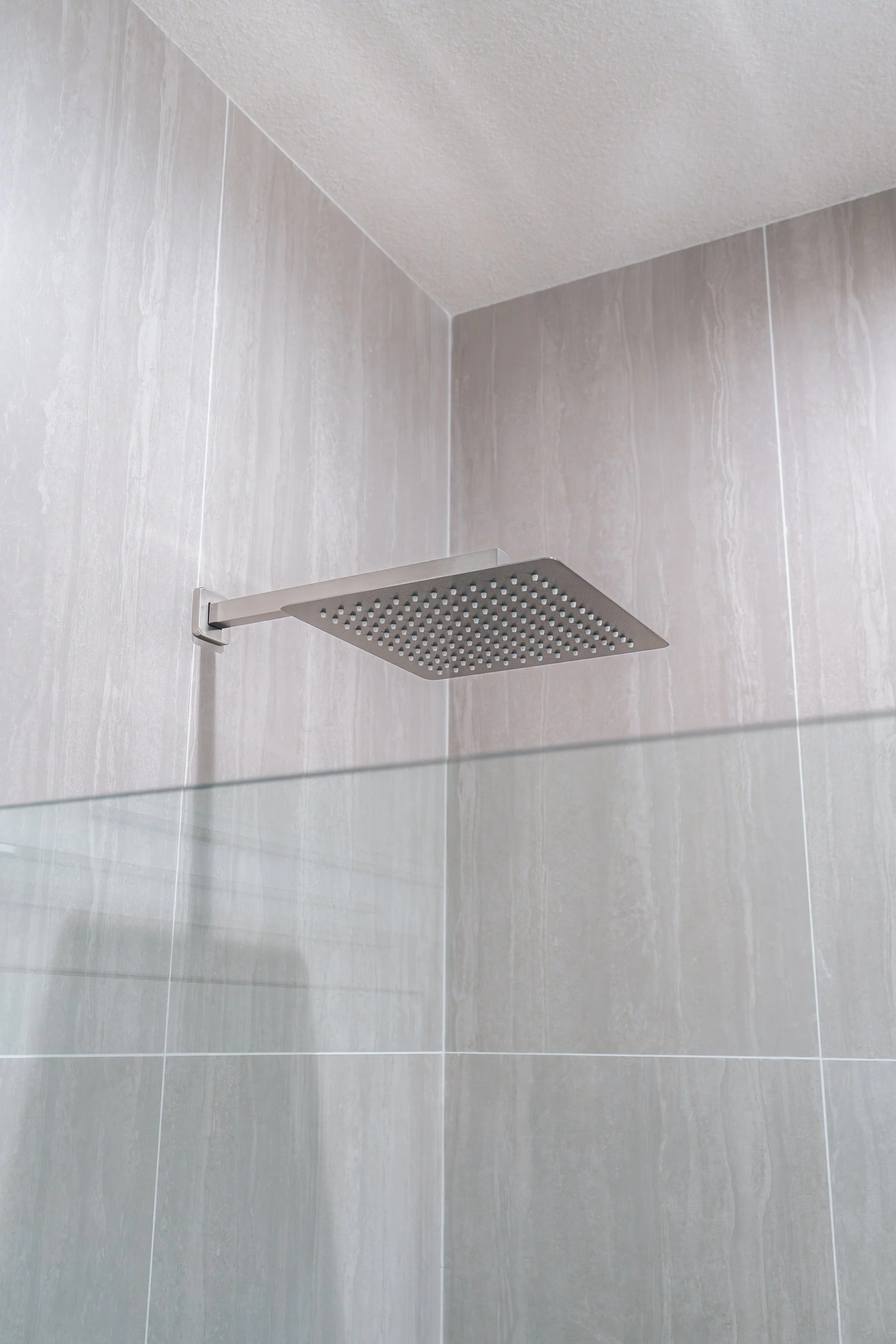 Close-up of a square shower head mounted on a tiled bathroom wall.