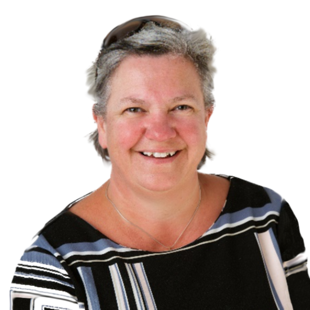 A woman with short gray hair wearing sunglasses on her head, a black and white striped top, and a necklace, smiling at the camera.