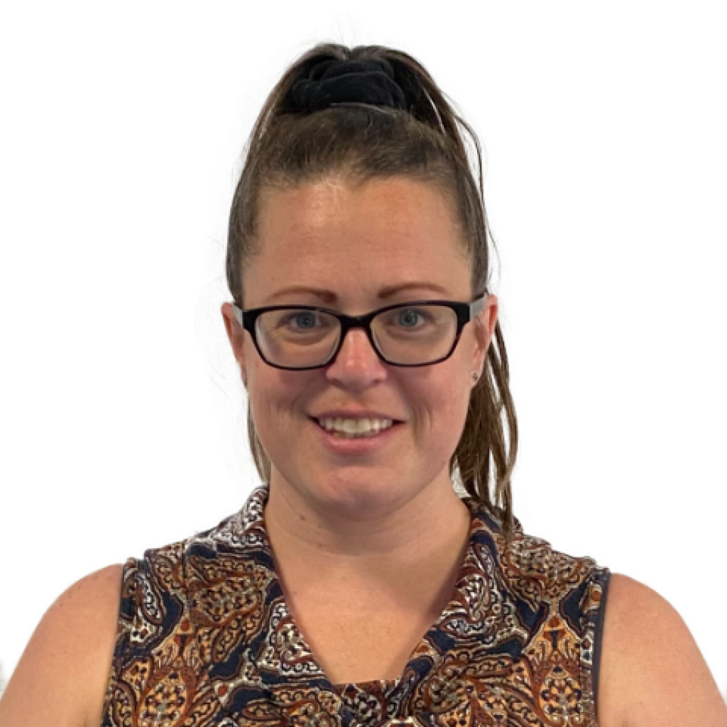 A woman with glasses, dark brown hair pulled back in a high ponytail, smiling, wearing a patterned sleeveless top.