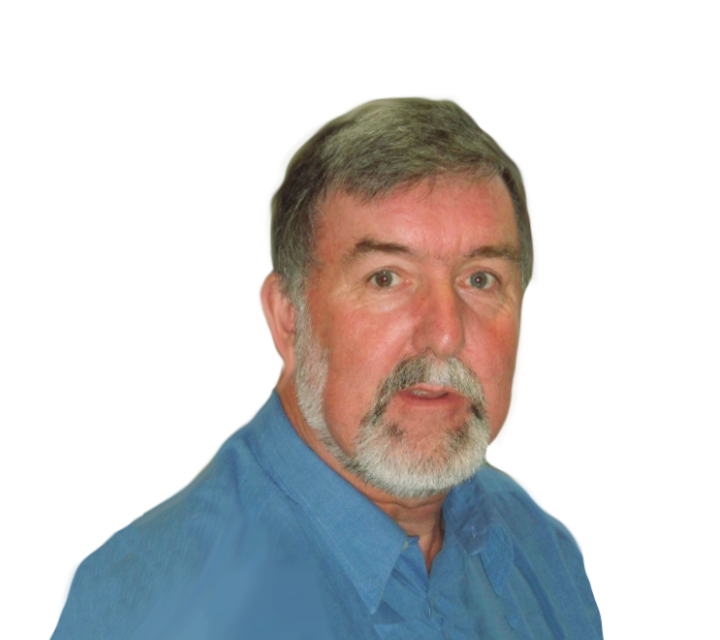 A middle-aged man with gray hair and a beard, wearing a blue collared shirt, looking at the camera with a surprised or curious expression.