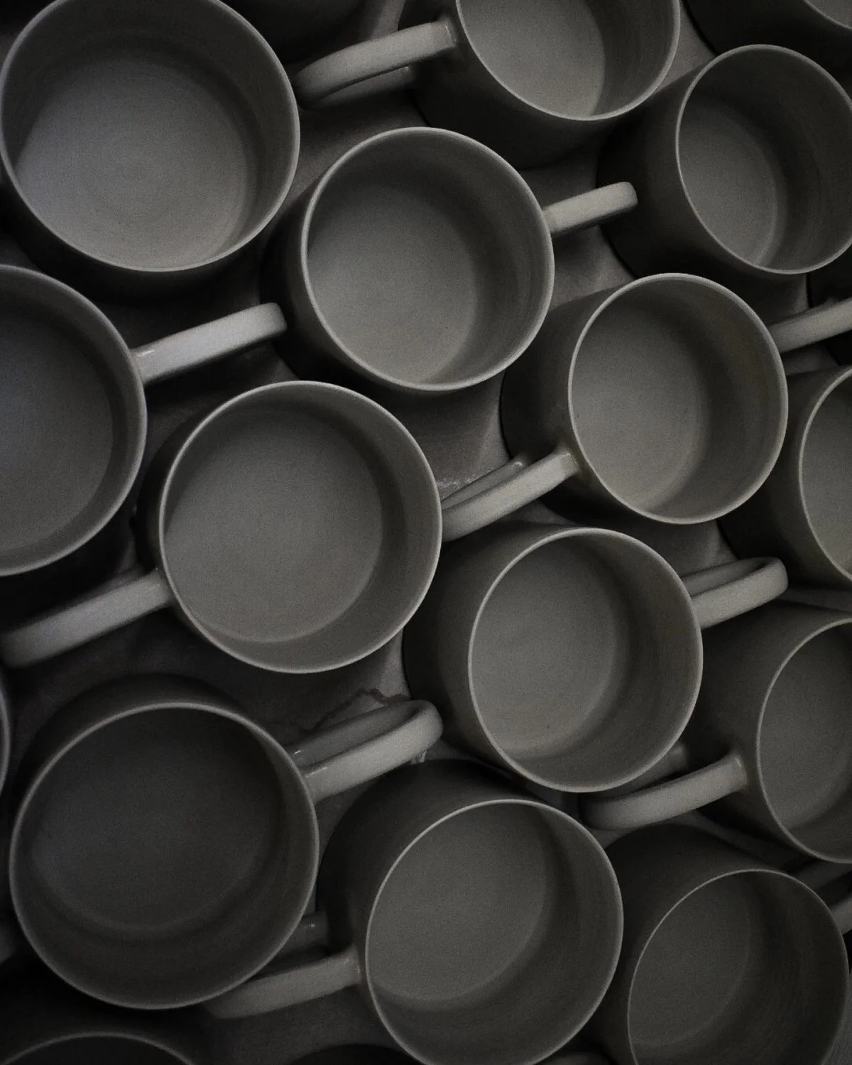 A close-up view of multiple gray ceramic mugs stacked together.