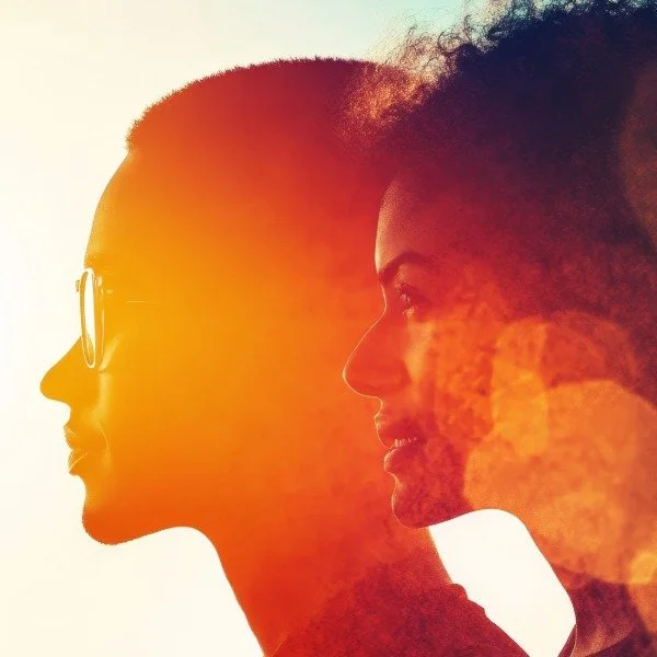 Silhouette of two women facing each other with sunlight creating a warm glow and lens flare.