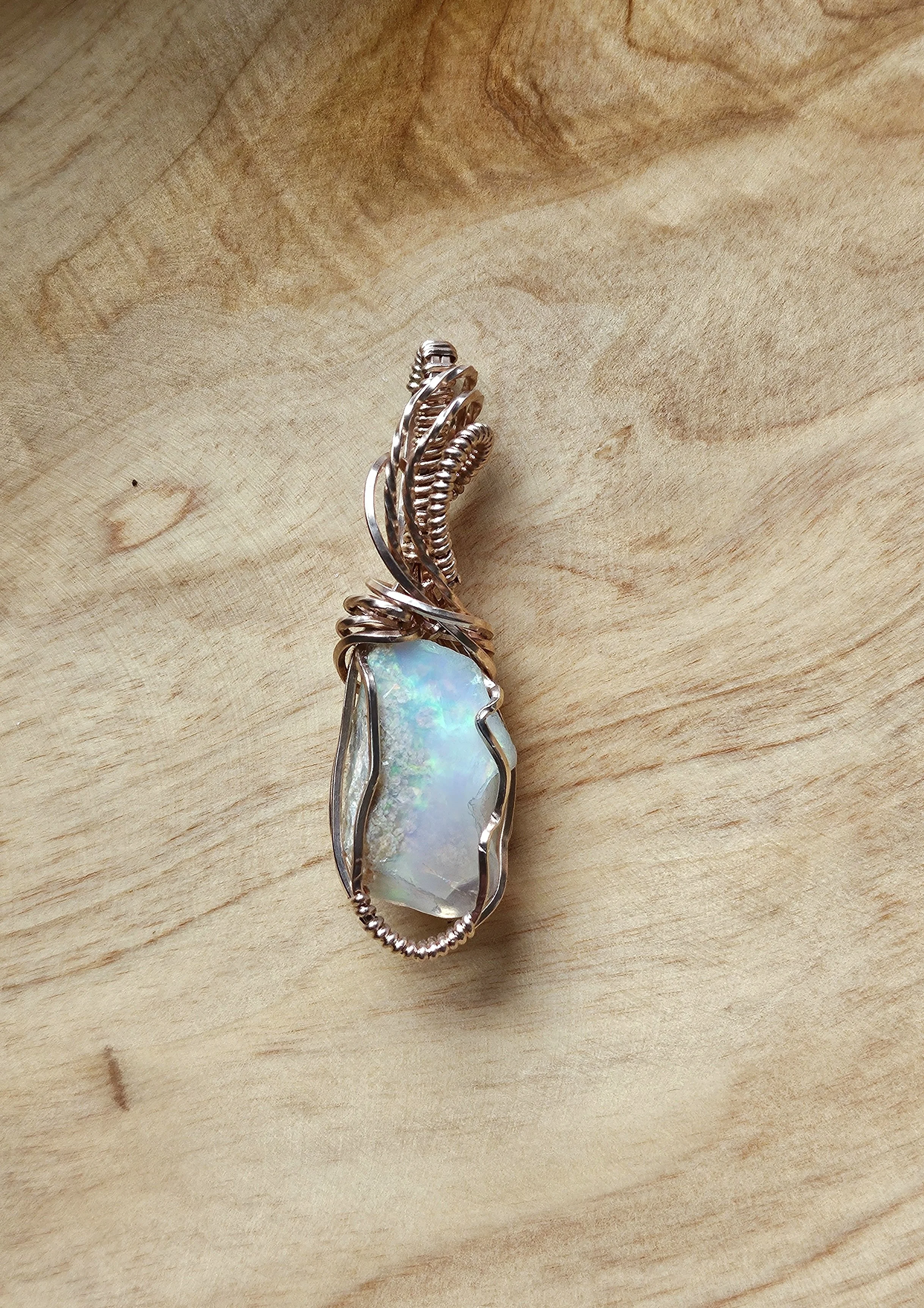 Silver ring with a large opal gemstone on a wooden surface.