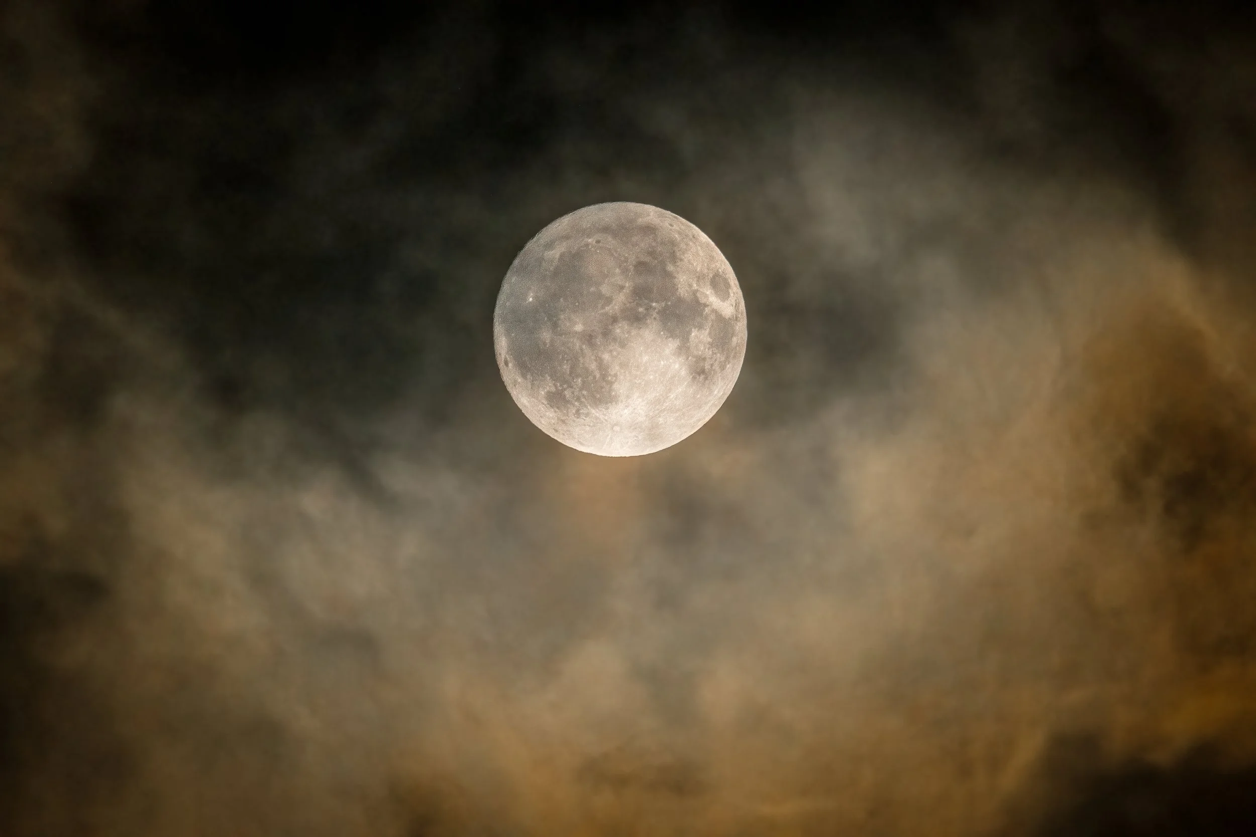 Full moon visible in dark cloudy sky.