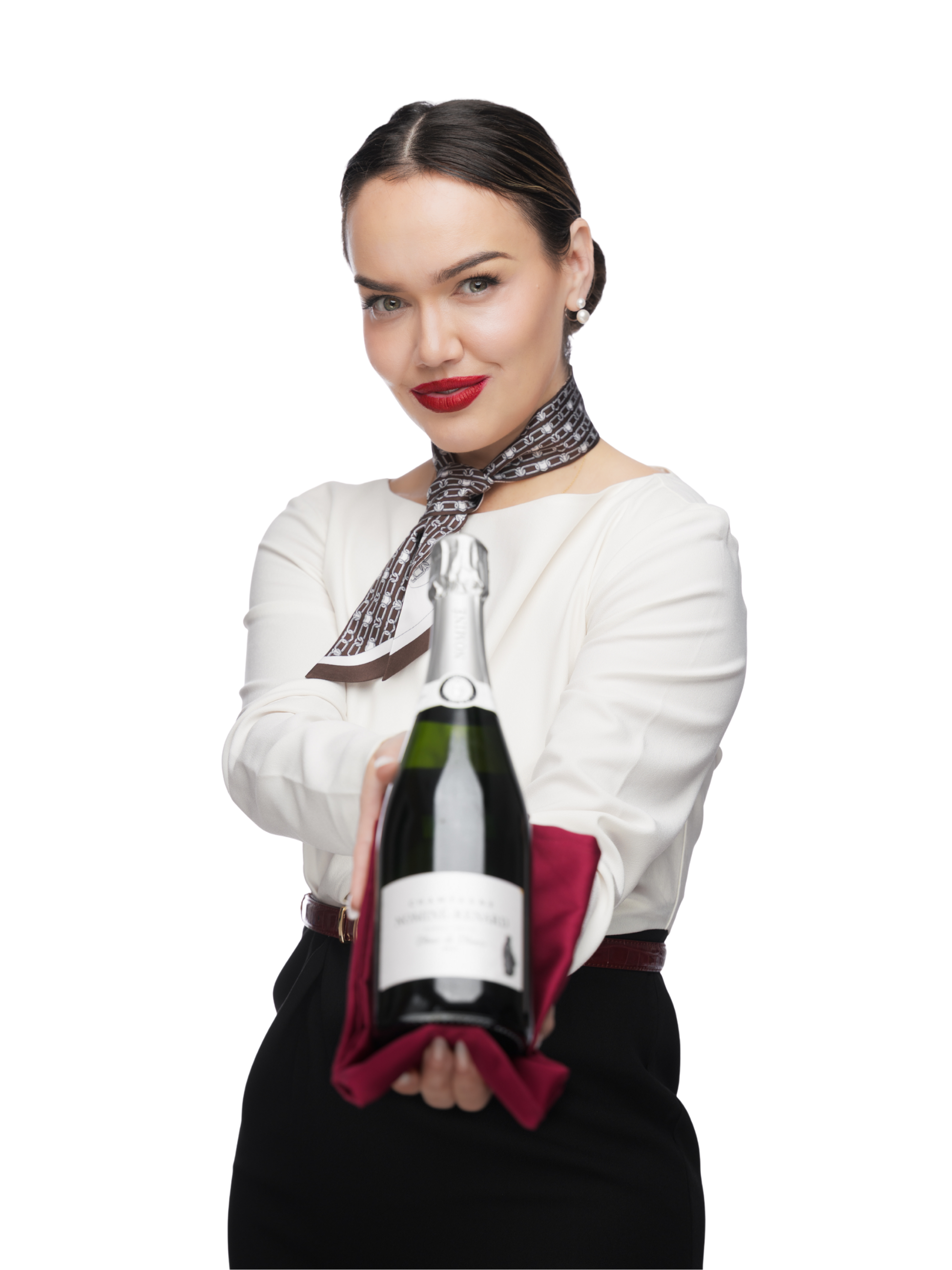 A woman with dark hair, red lipstick, and pearl earrings holding a bottle of champagne wrapped in a red cloth.