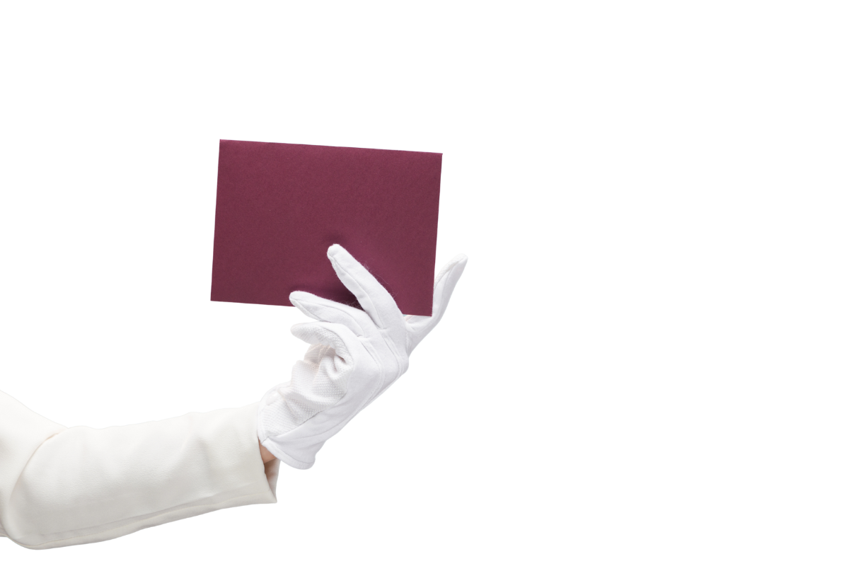 A person wearing a white glove is holding a maroon fabric swatch or sample against a white background.