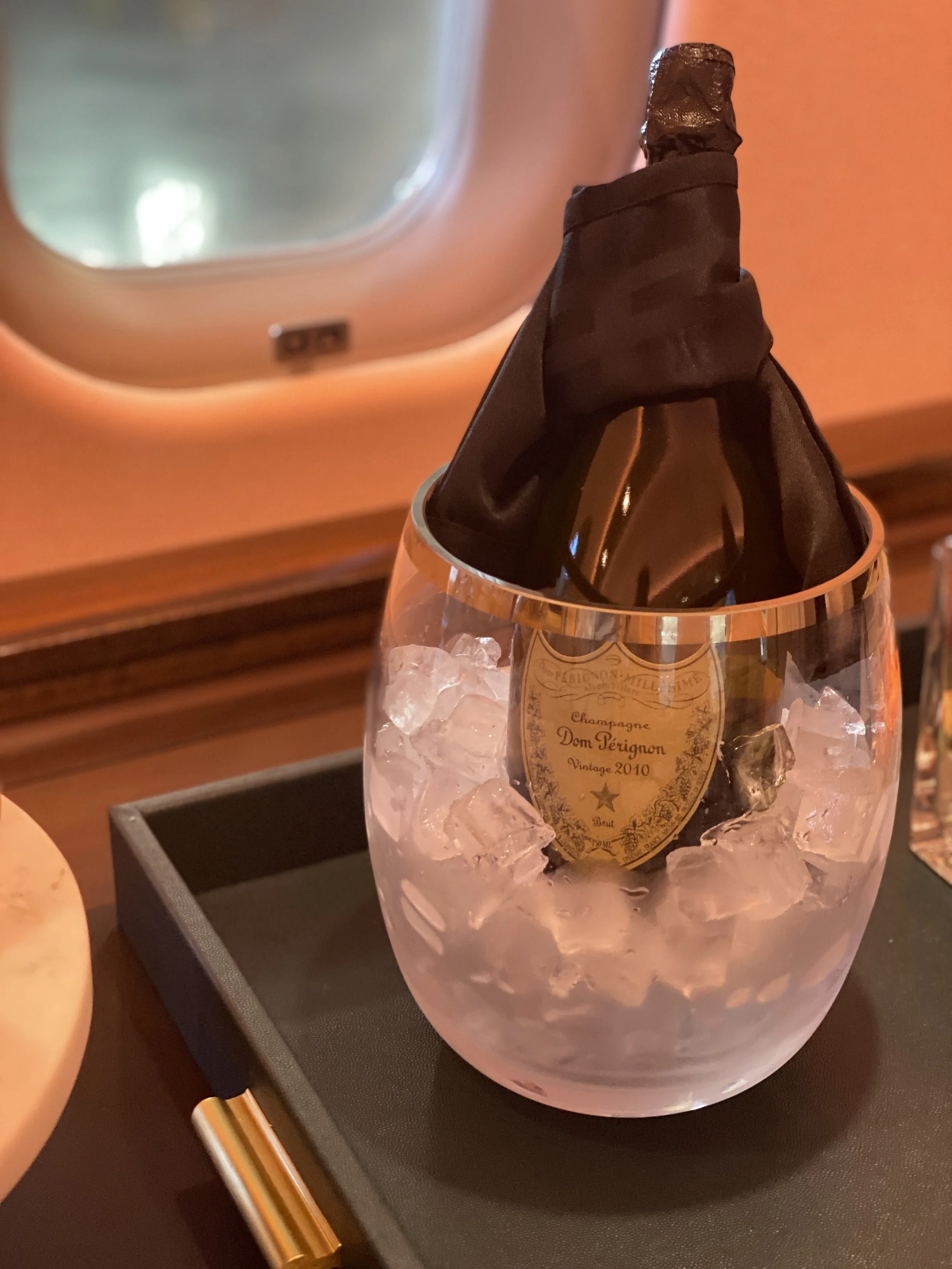 A bottle of champagne wrapped in a black cloth inside a glass with ice.