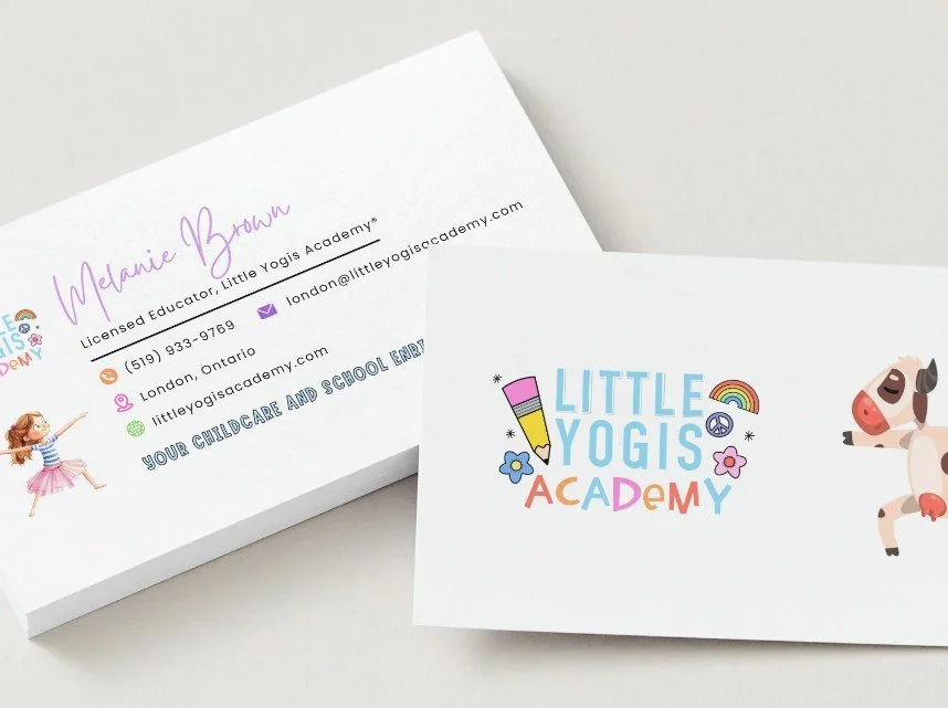 Business cards for Little Yogis Academy featuring colorful, playful text, a pencil illustration, a rainbow, peace sign, flowers, and cartoon animals including a girl pointing and a cow.