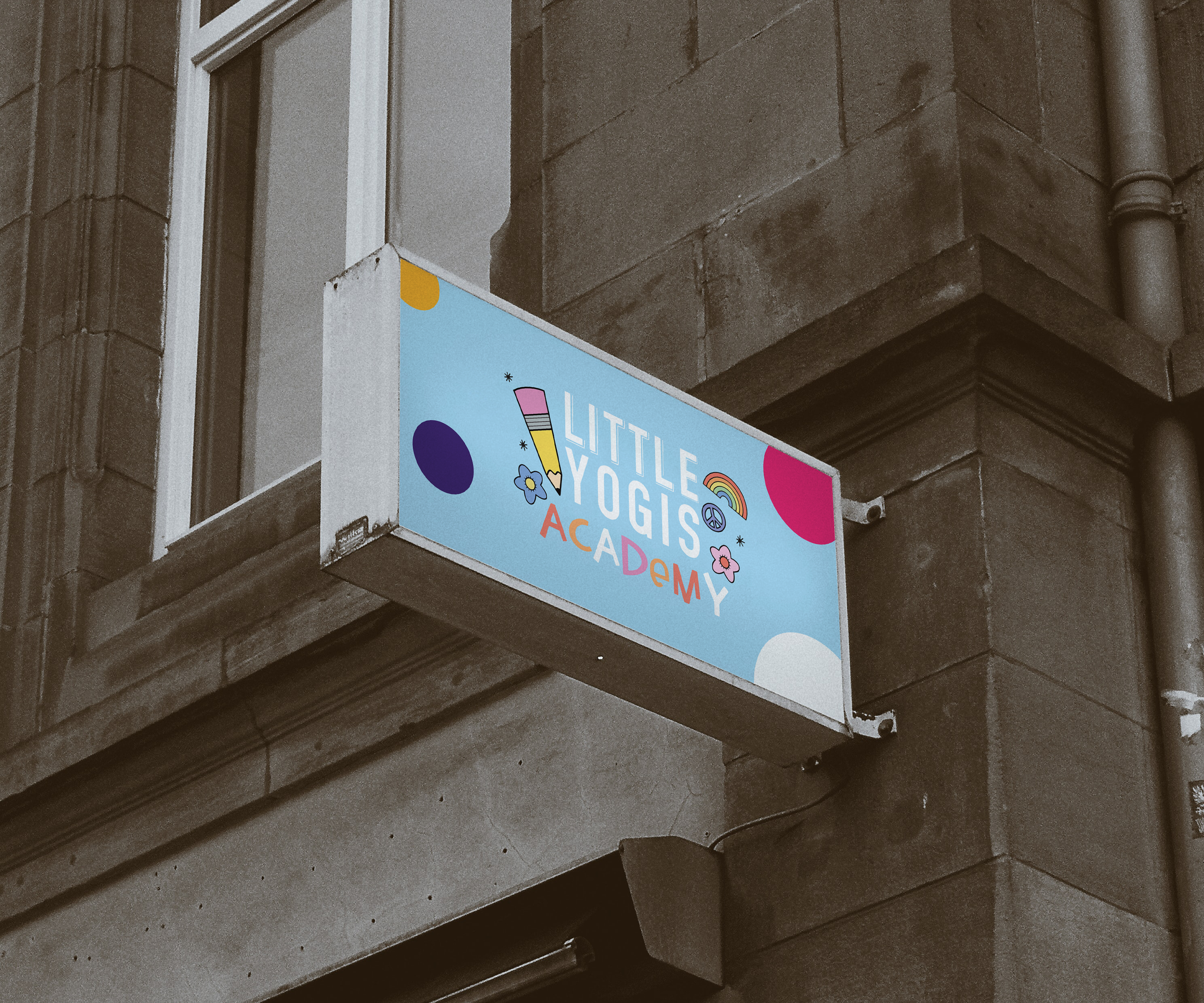 Colorful sign for Little Yogis Academy attached to a building's exterior wall.