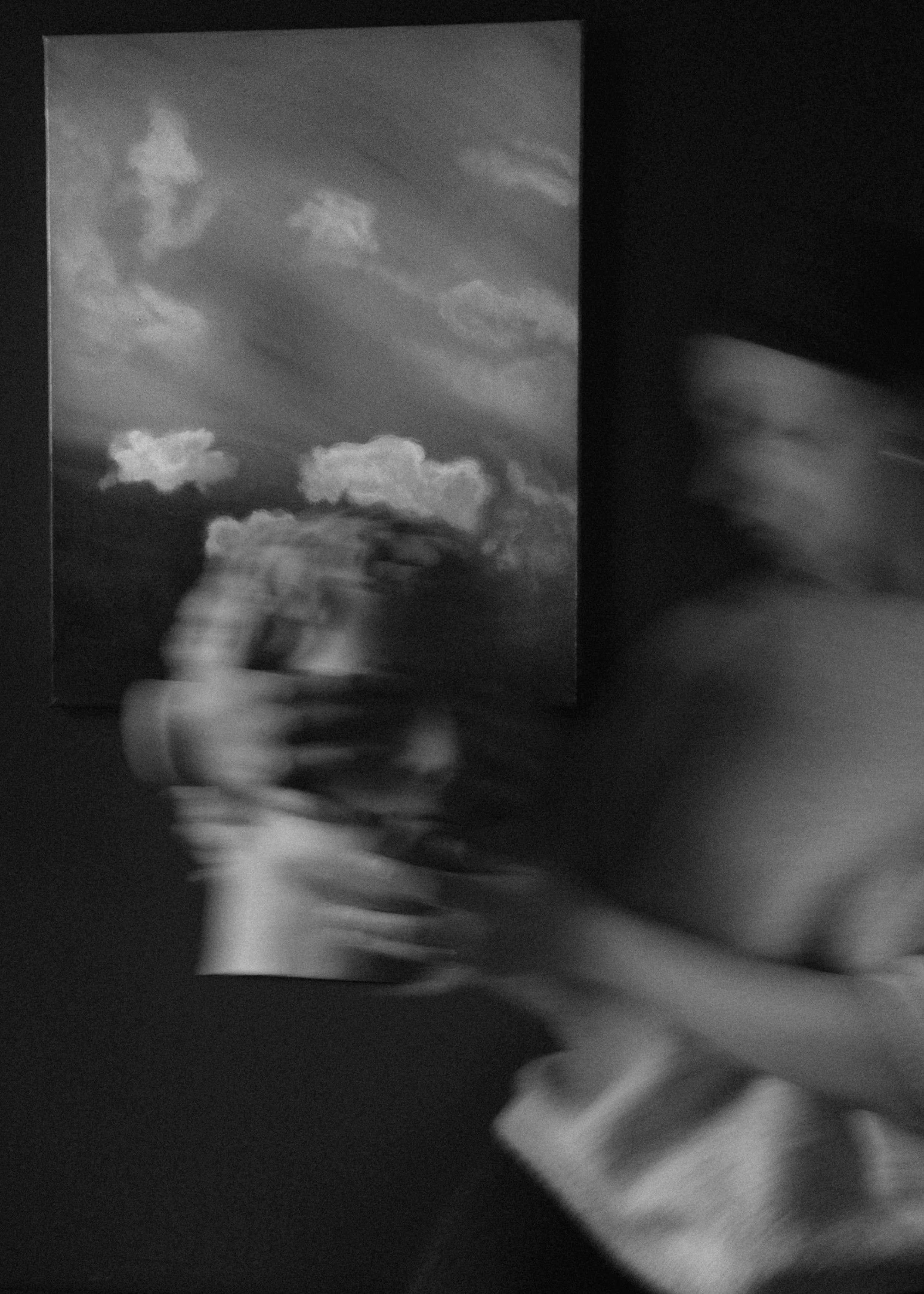 Blurred person holding a picture of clouds in black and white.