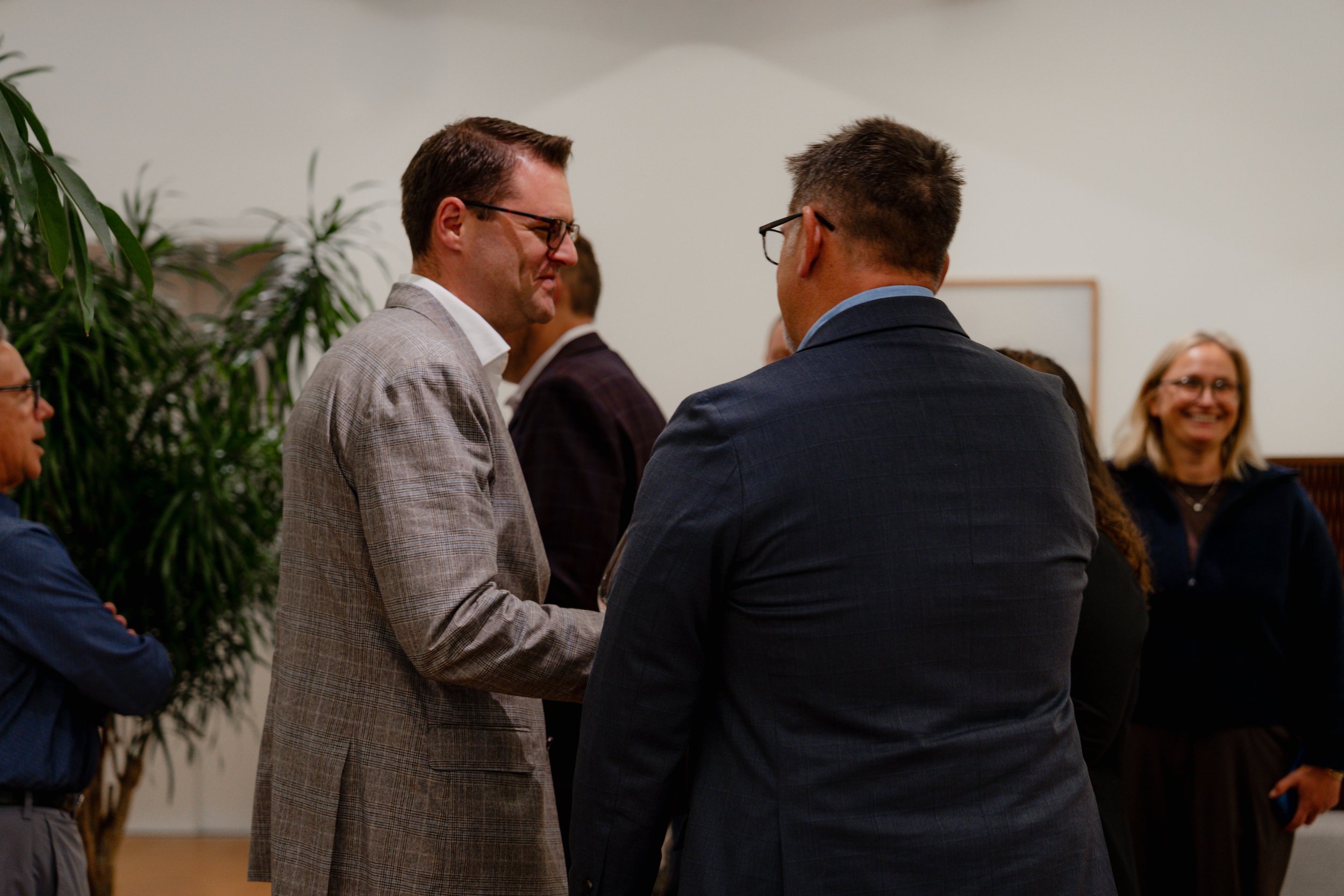 Group of people talking and smiling at an indoor event.