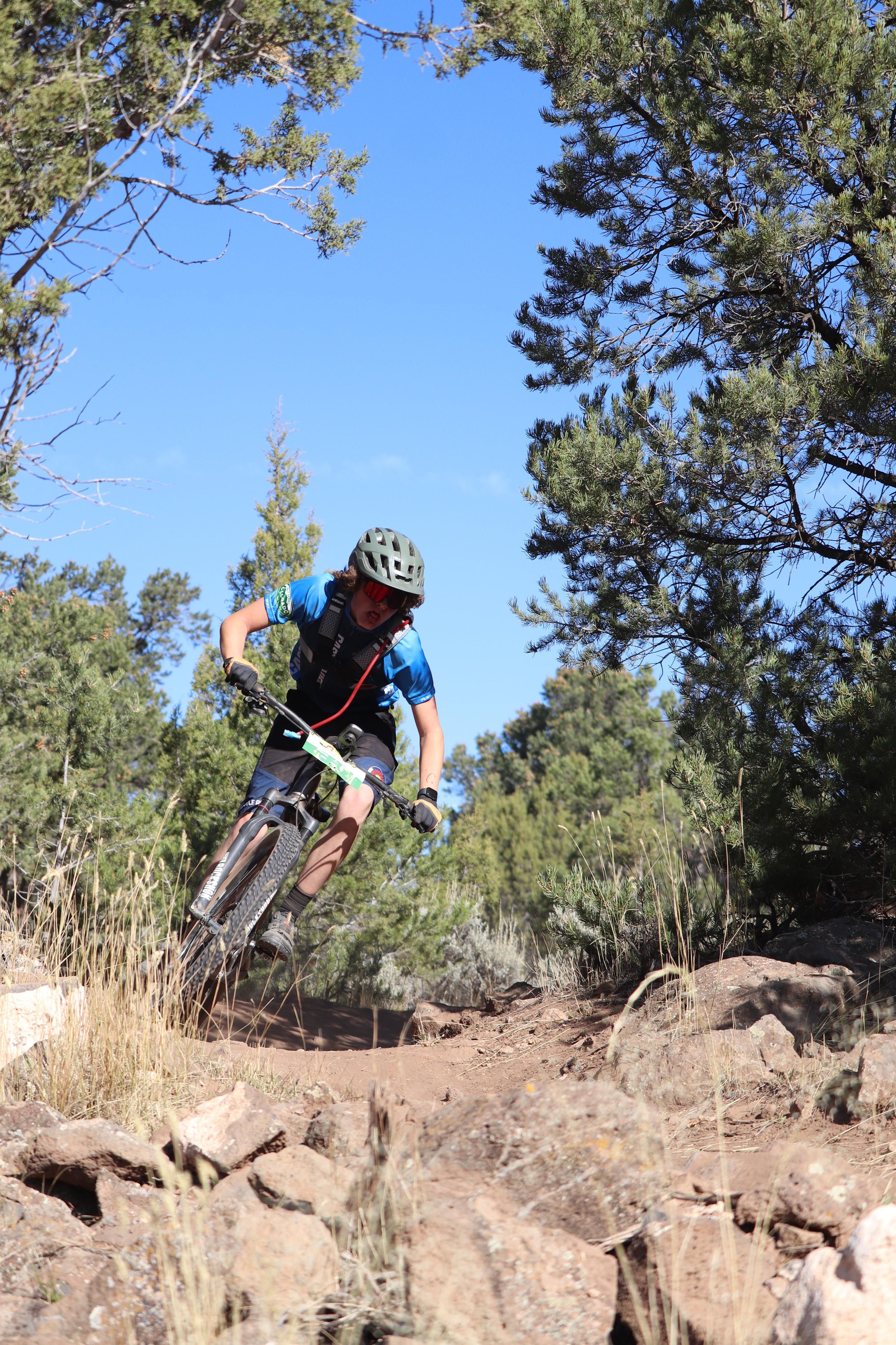 A person riding a mountain bike on a rocky trail through a forest.