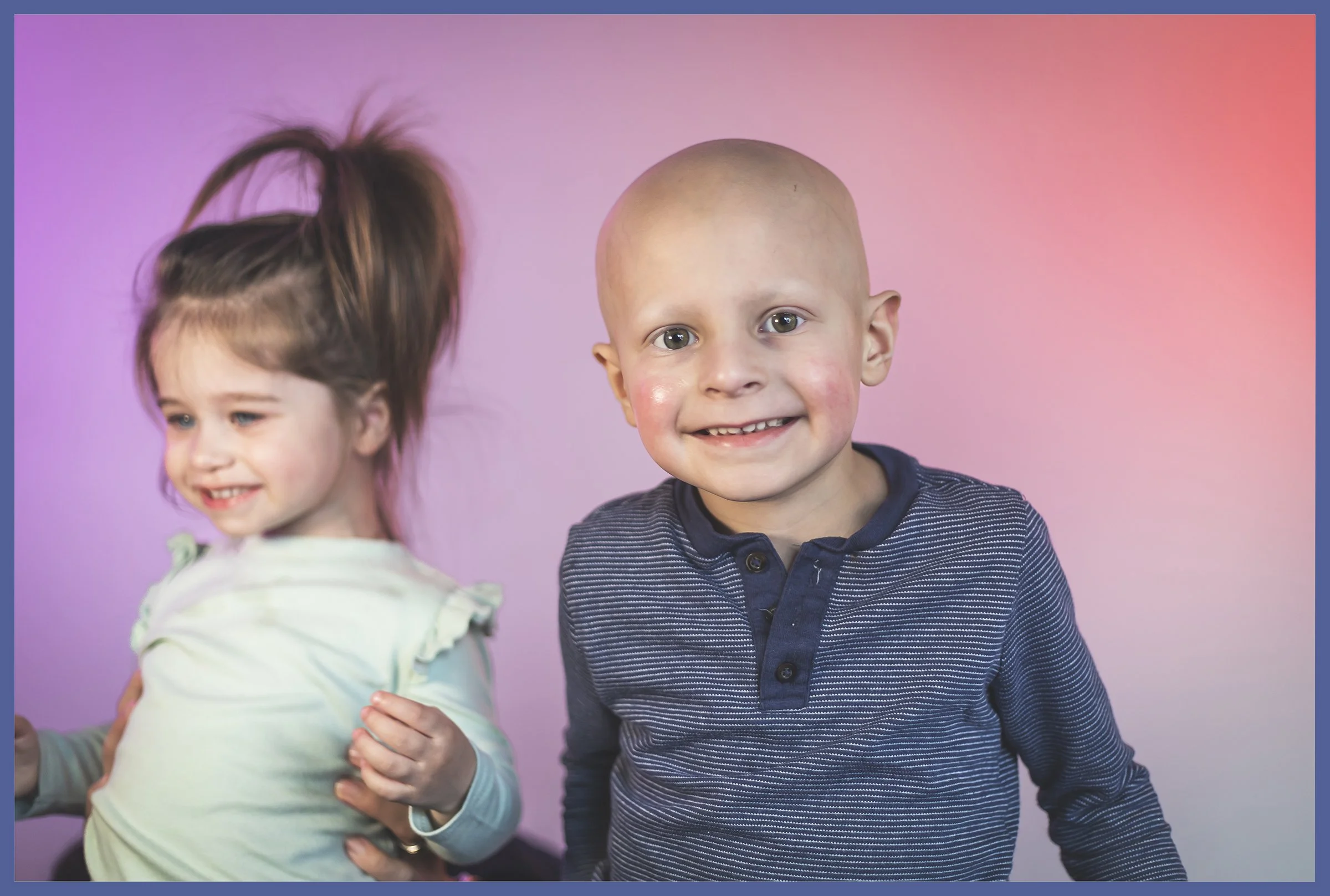 Two young children, a girl with long brown hair tied up and a boy with a bald head, smiling against a pink and purple gradient background.