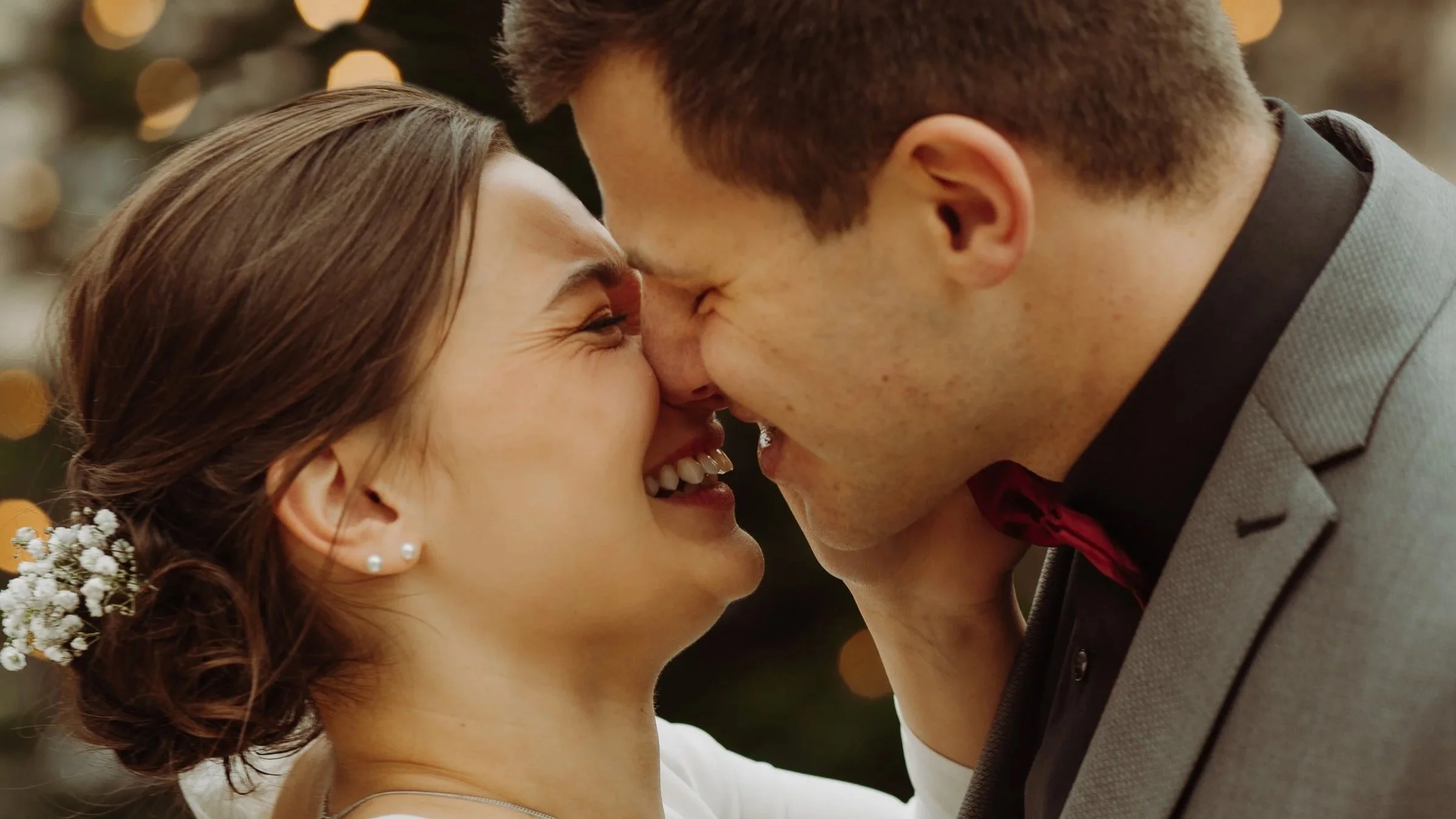 Ein glückliches Paar bei einer Hochzeit, das sich mit der Stirn berührt und lächelt.