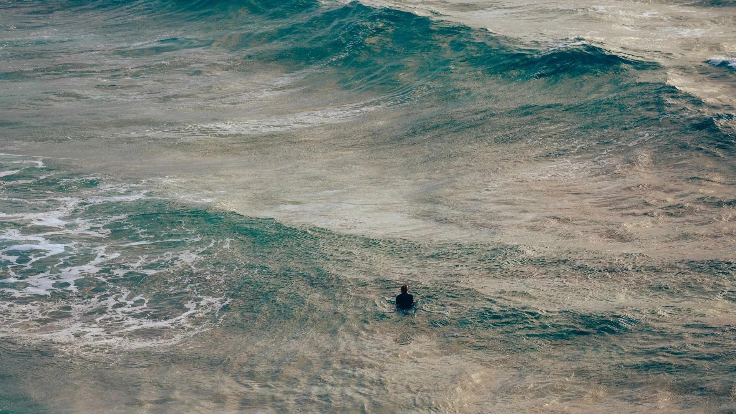 Ein Mensch, der im Meer schwimmt, umgeben von Wellen.