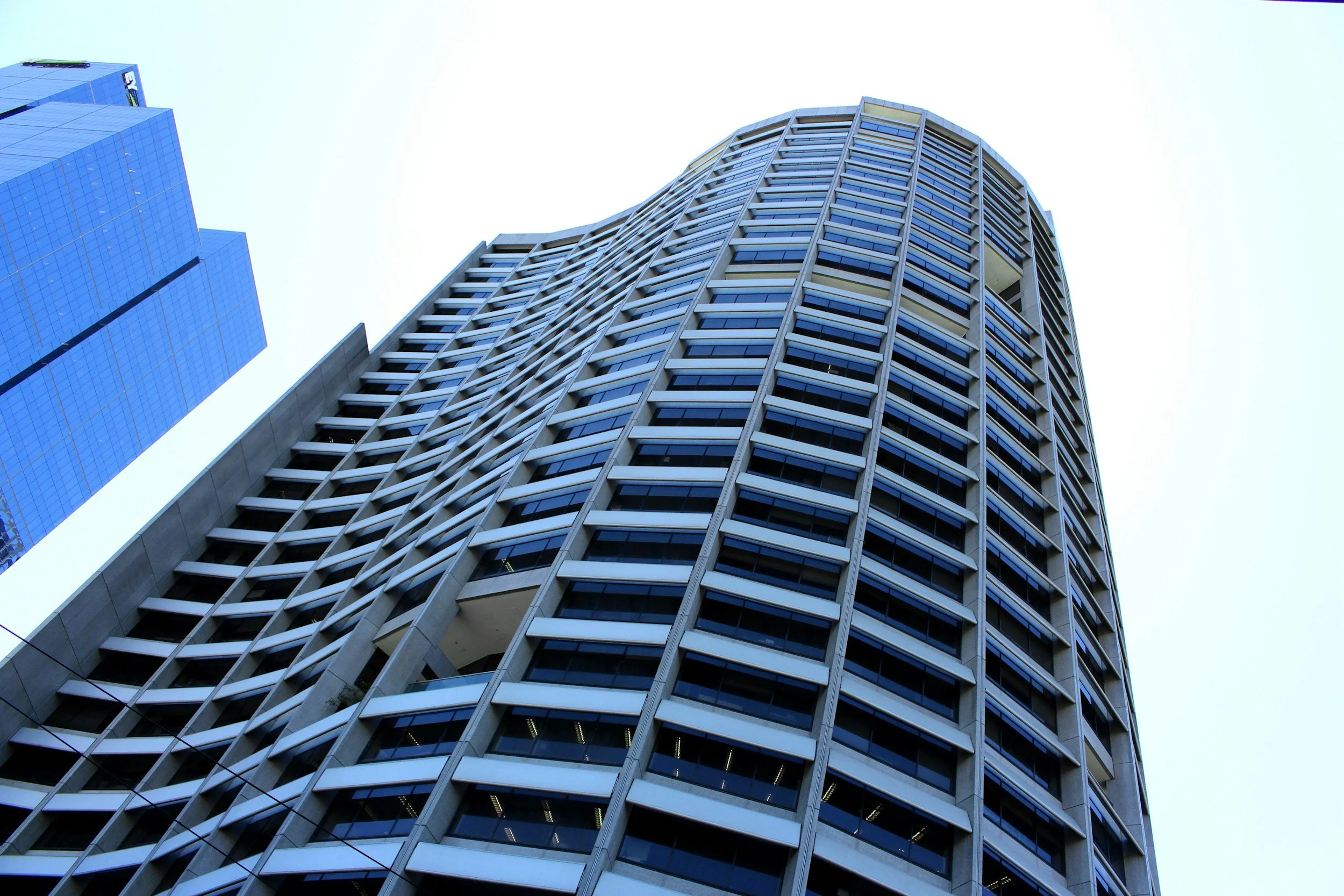Low-angle view of modern high-rise building with glass windows and curved architecture.
