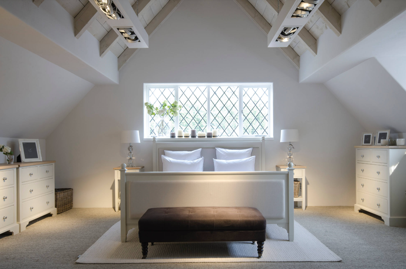 Vaulted ceiling London loft bedroom by design and build architects, featuring exposed beams, diamond pane window, and bespoke storage solutions.