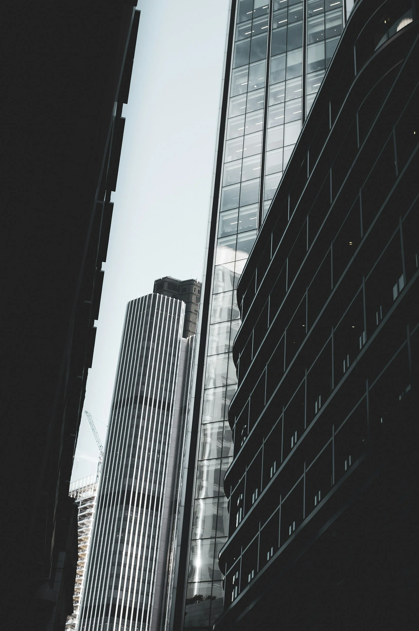 Looking up at modern skyscrapers with glass exteriors in an urban cityscape.