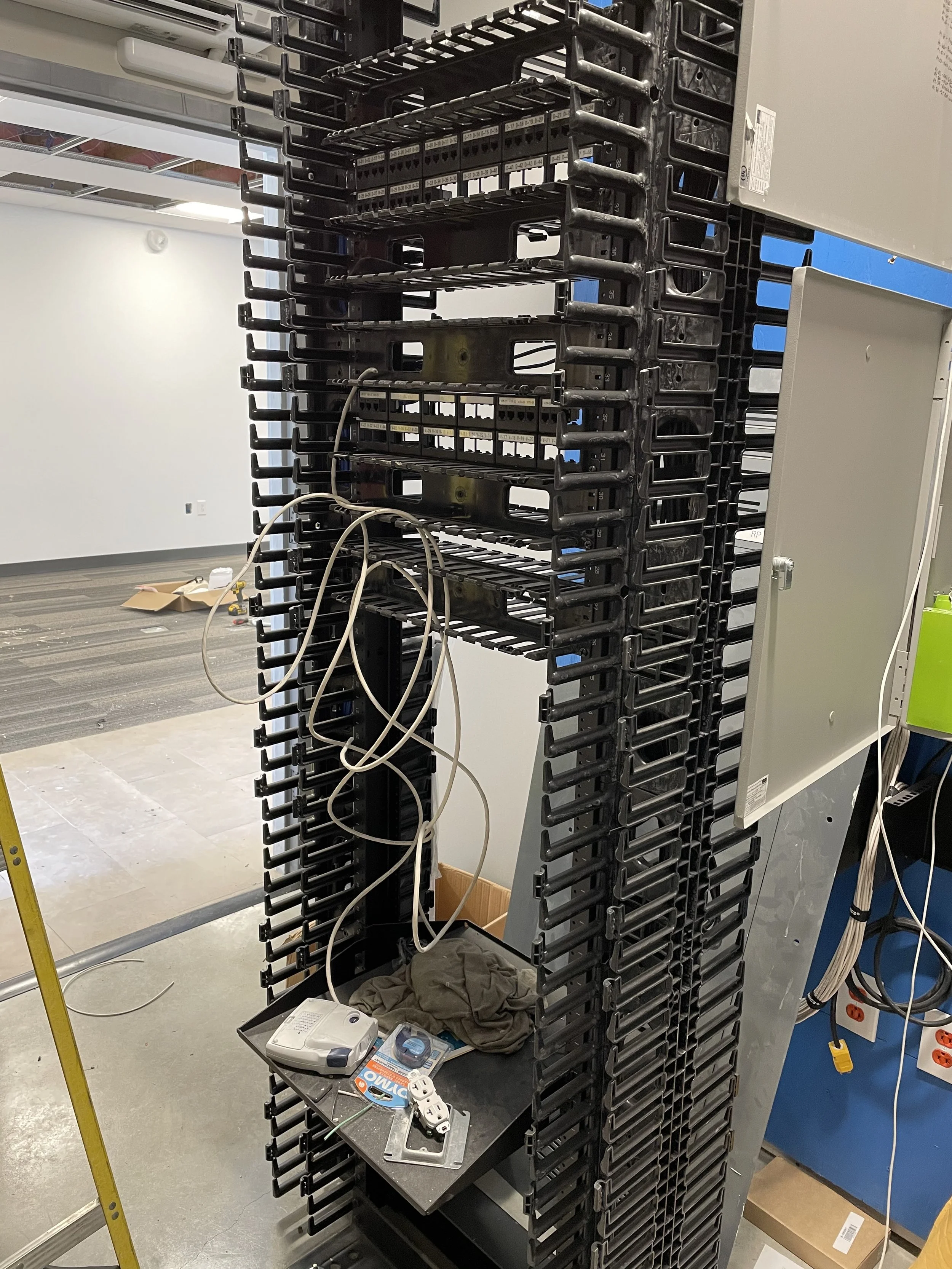 Empty server rack with some wires and miscellaneous tools on a small black table at the bottom.