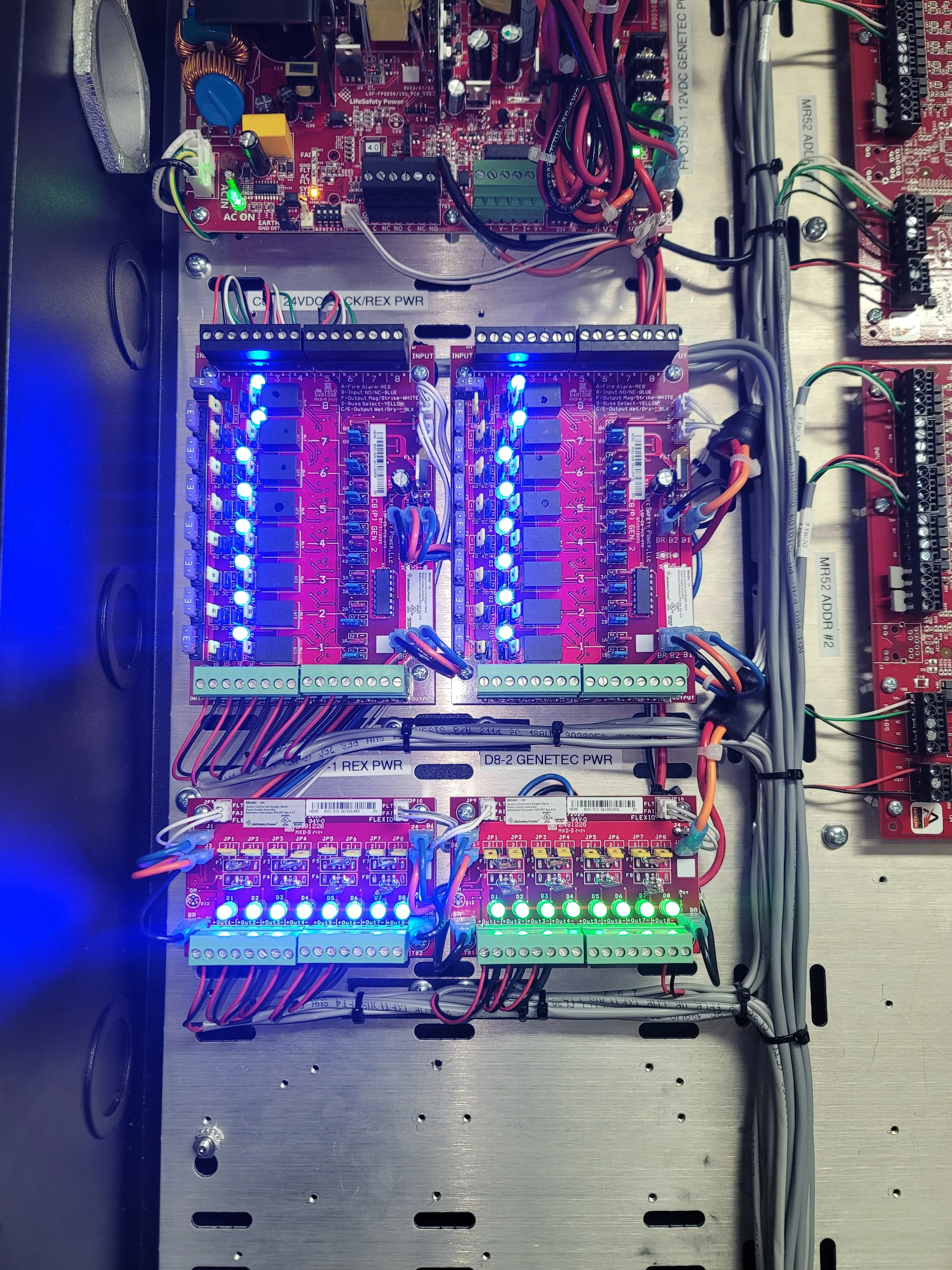 Close-up of electronic circuit boards with LED lights and wiring, mounted on metal framework.