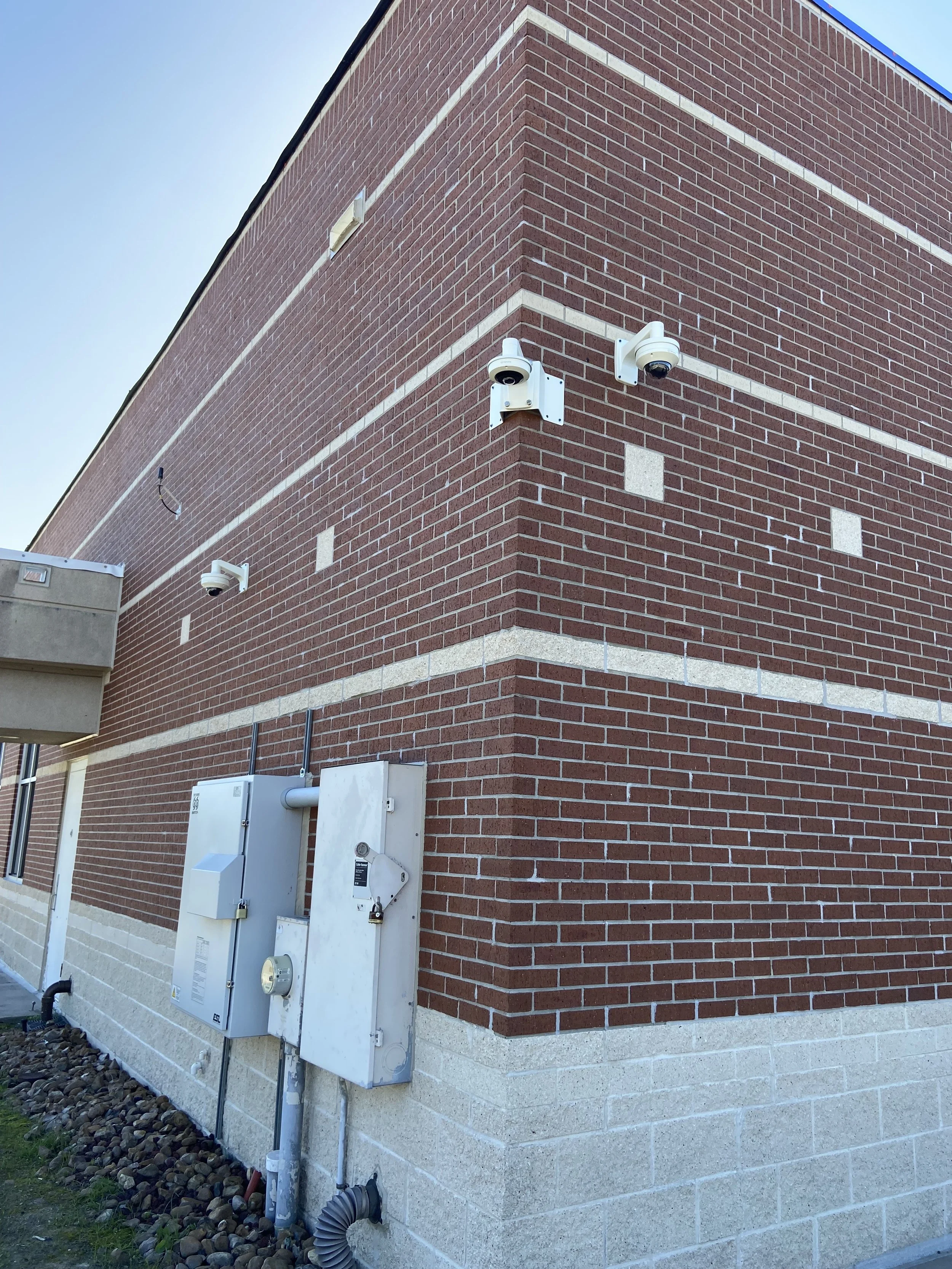 Security cameras mounted on a brick exterior wall of a building.