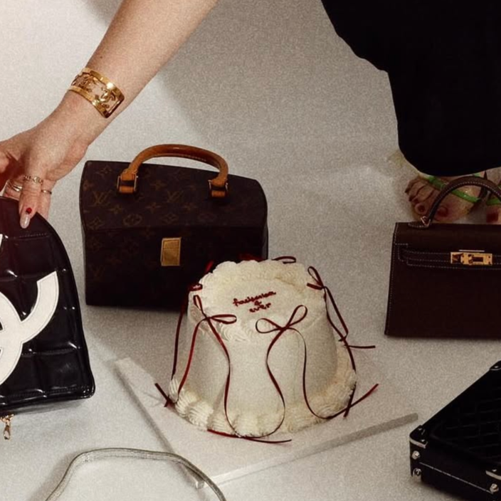 Various handbags and a drawstring bag displayed on a flat surface, with a person's hand and arm visible.