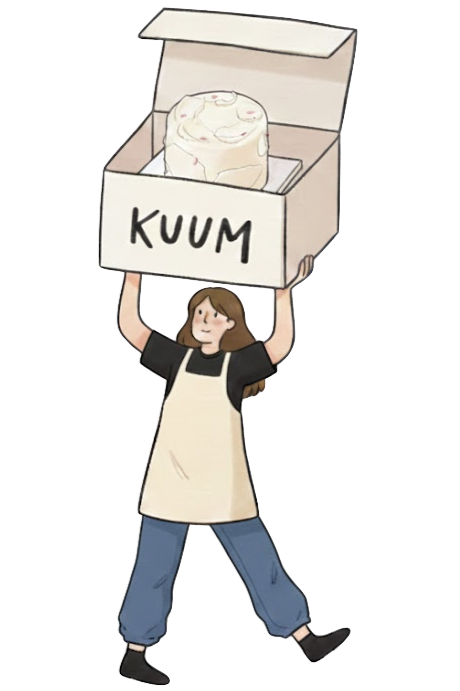 A person holding a box labeled 'KUUM' containing a large round cheese wheel.