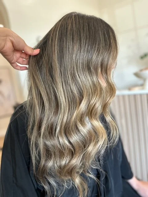 Side view of a woman with long, wavy, bronde hair in a luxury hair salon.
