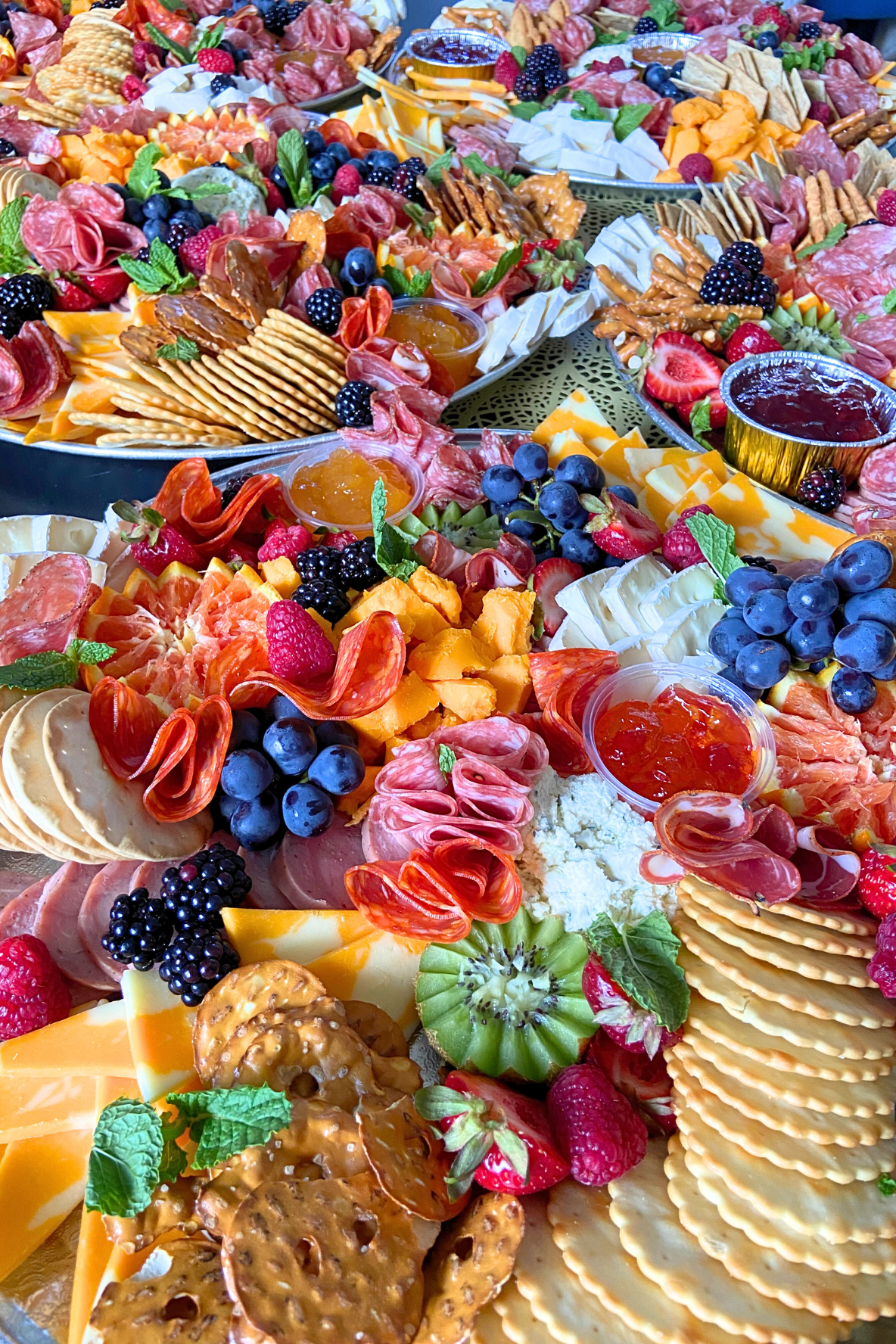 Assorted charcuterie board with cheeses, crackers, fruits, berries, and spreads.