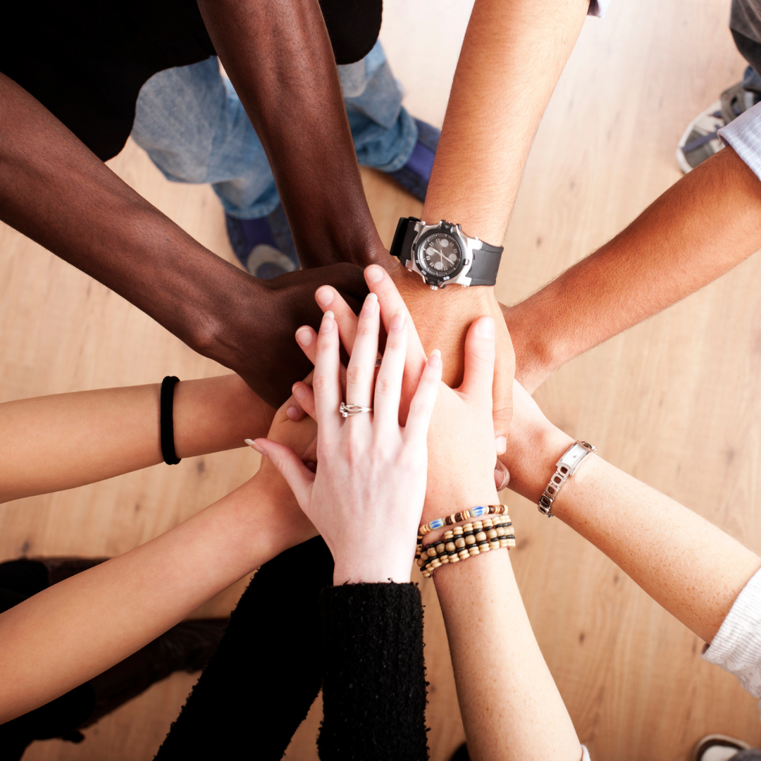Group of diverse people stacking hands in unity.