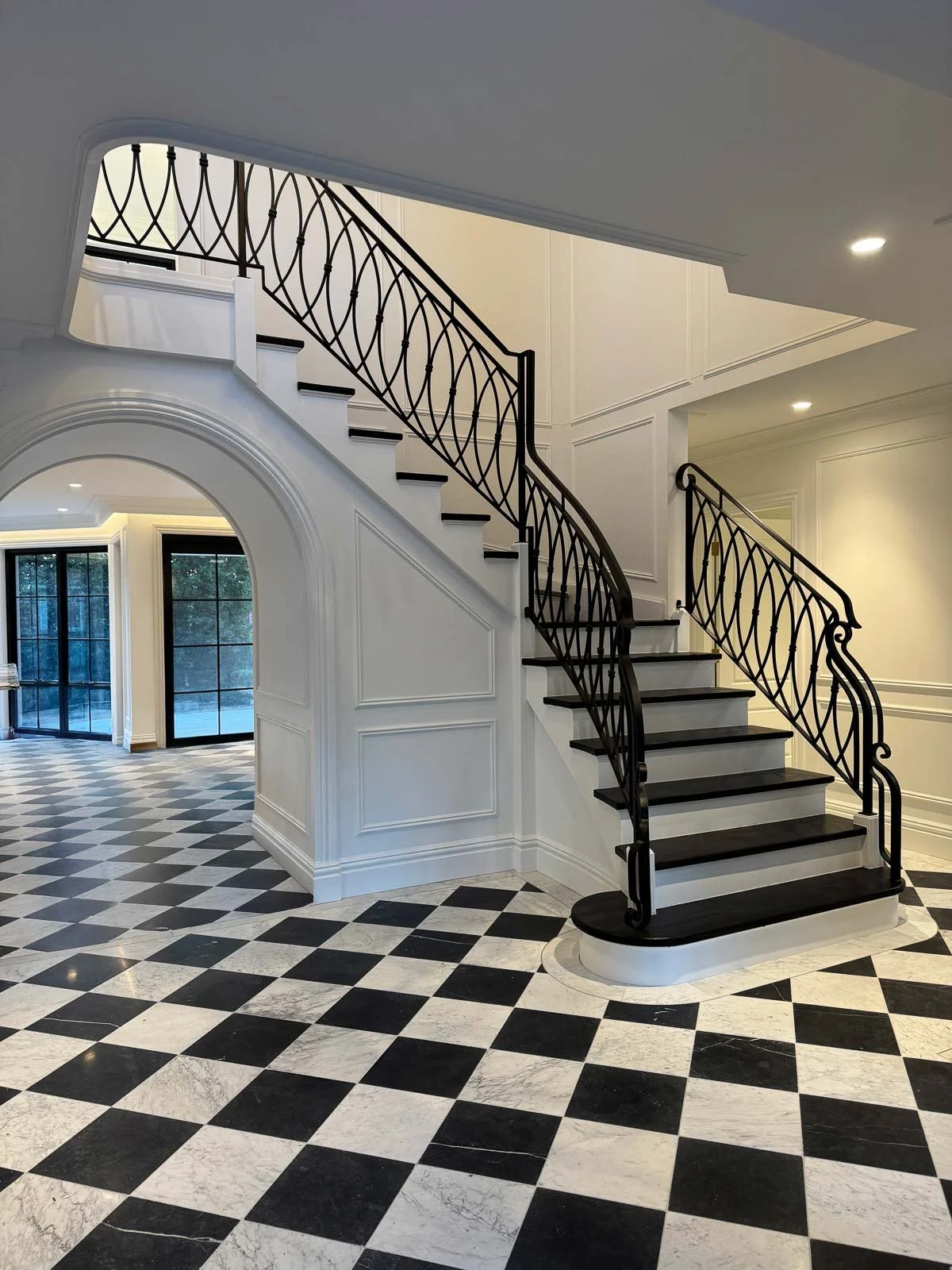 Interior of a house with a black and white checkered marble floor and a staircase with black wrought iron railing. Staircase Polishing Sydney