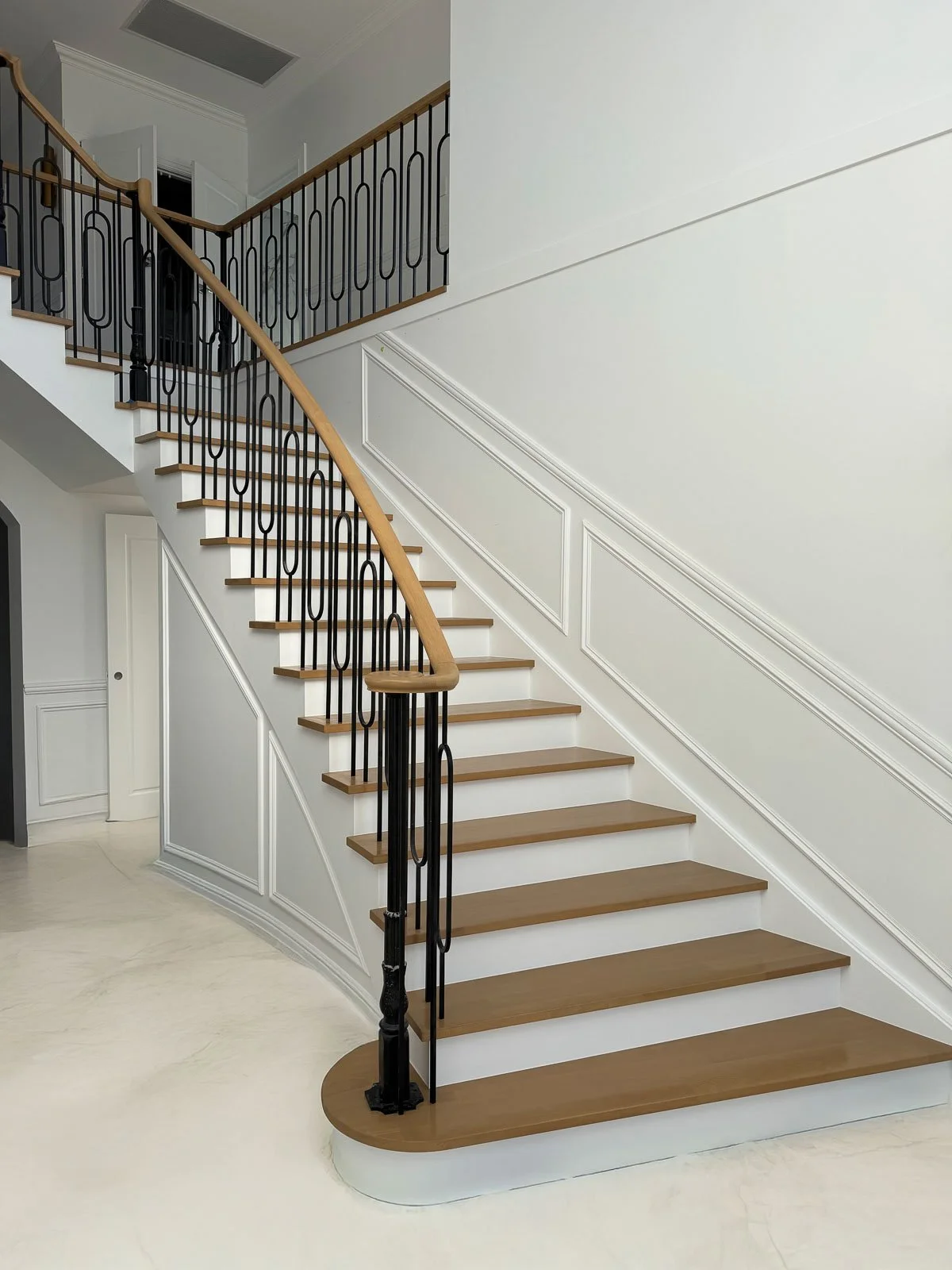 Interior view of a staircase with wooden steps, black metal railing, and light-colored walls featuring decorative molding. Staircase Polishing Sydney