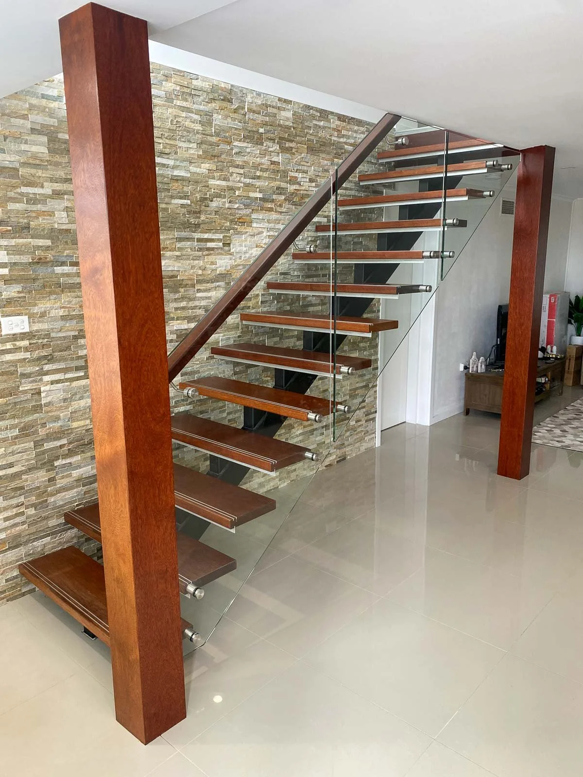 Modern staircase with wooden treads, glass sides, and wooden support beams in a contemporary home interior. Staircase Polishing Sydney