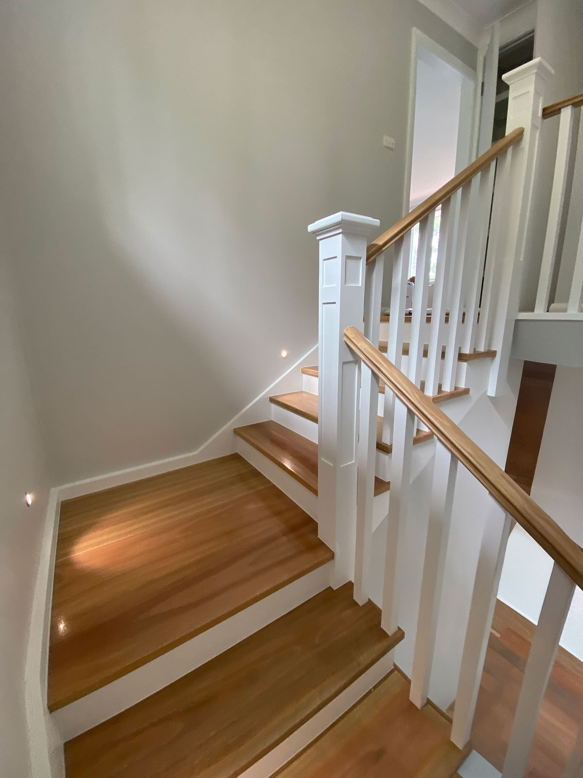 Photo of a staircase with wooden steps and white railings in a home interior. Staircase Polishing Sydney