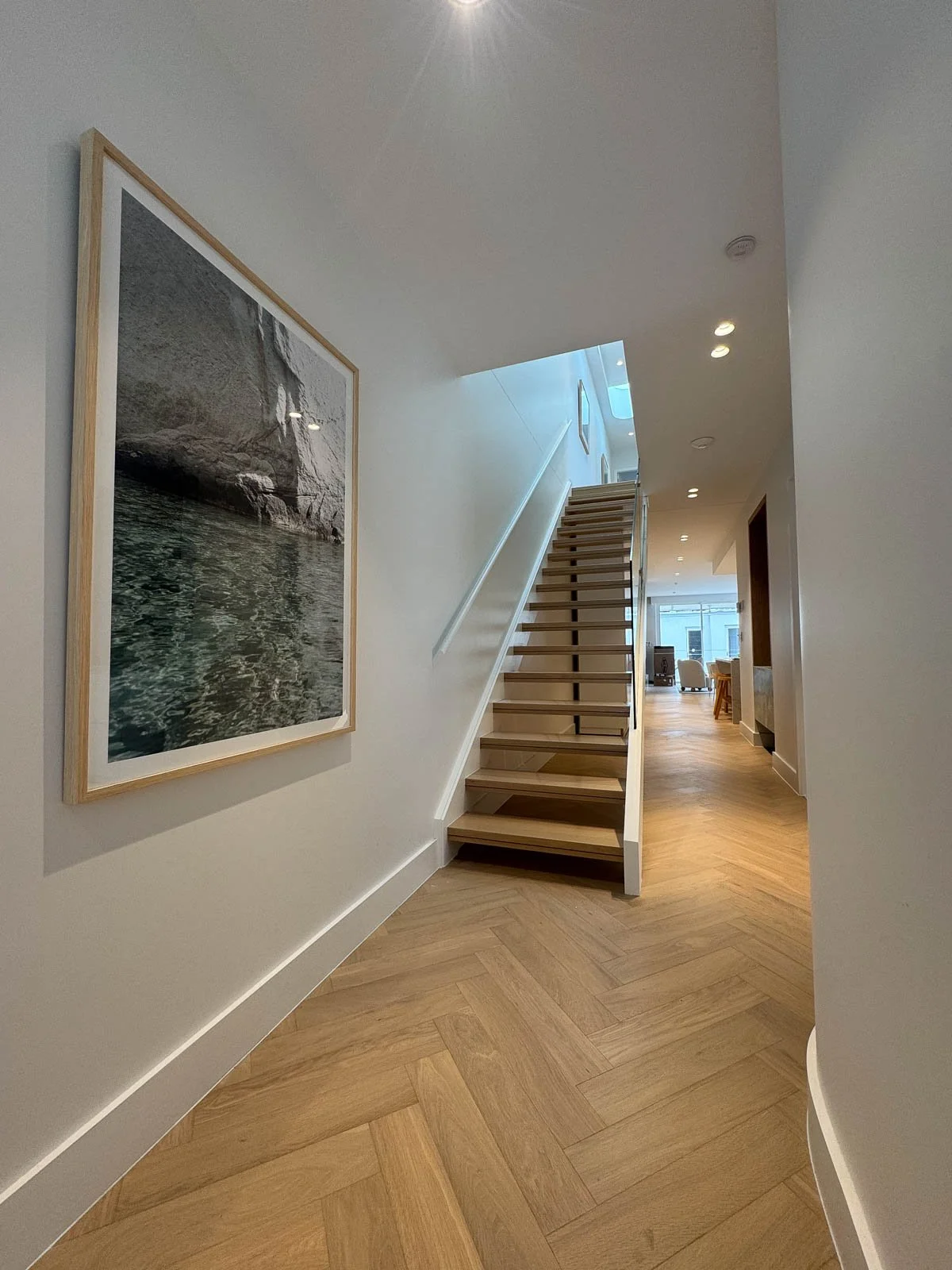 Interior view of a modern home with a staircase, framed artwork on the wall, and wooden flooring. Staircase Polishing Sydney