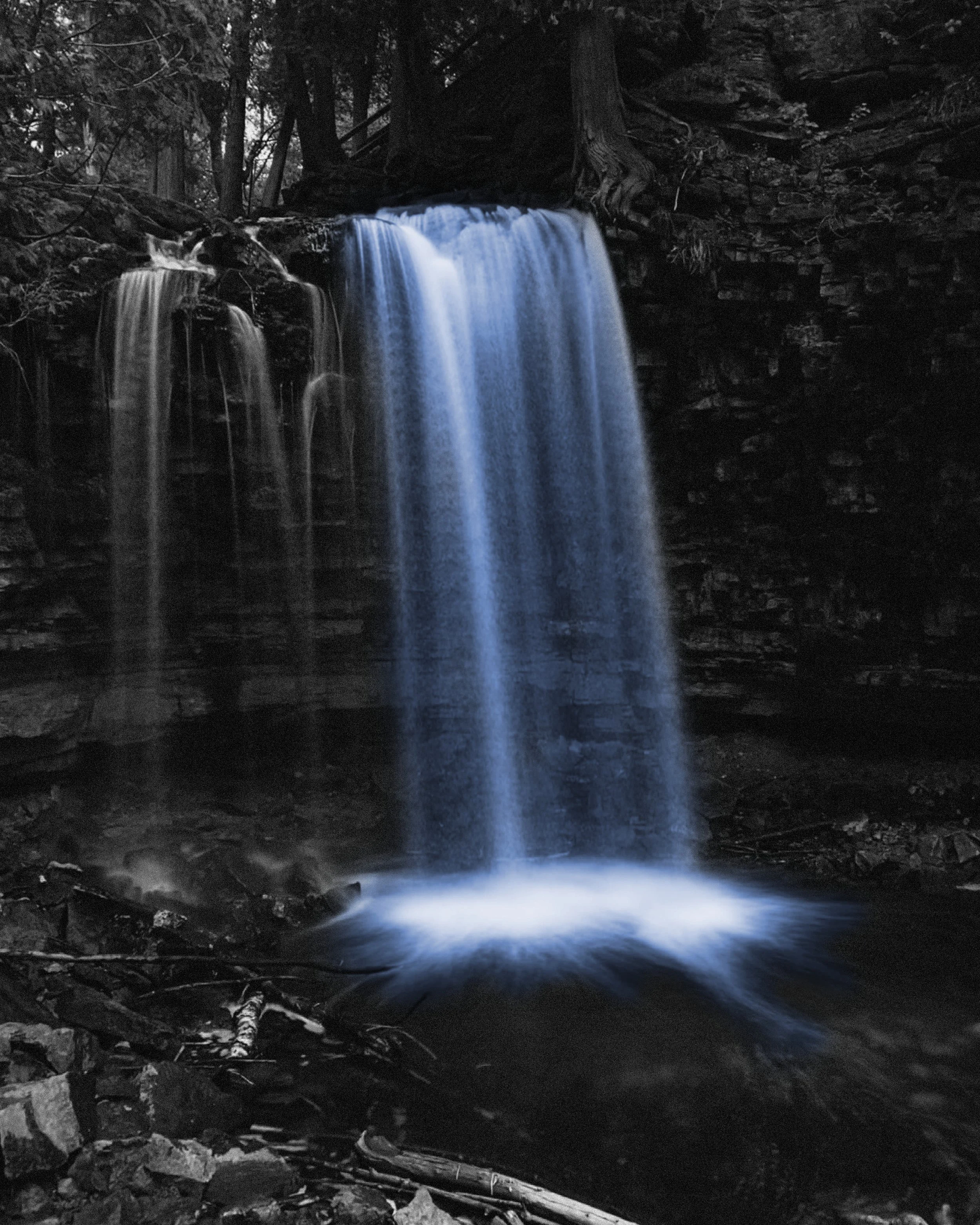 Black and white nature photo with blue waterfall
