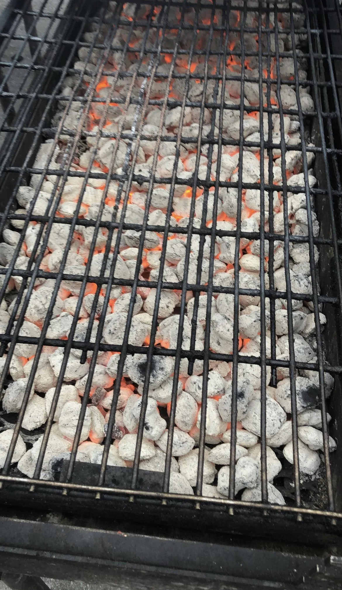 Charcoal and glowing red embers on a grill, ready for cooking food for Gobble Gobble Give Detroit to feed those in need.