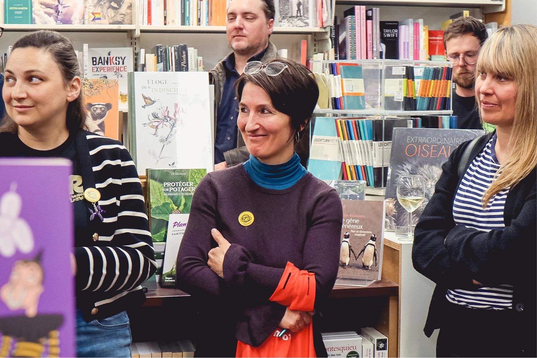 Groupe de cinq personnes dans une librairie, discutant, avec étagères de livres en arrière-plan.