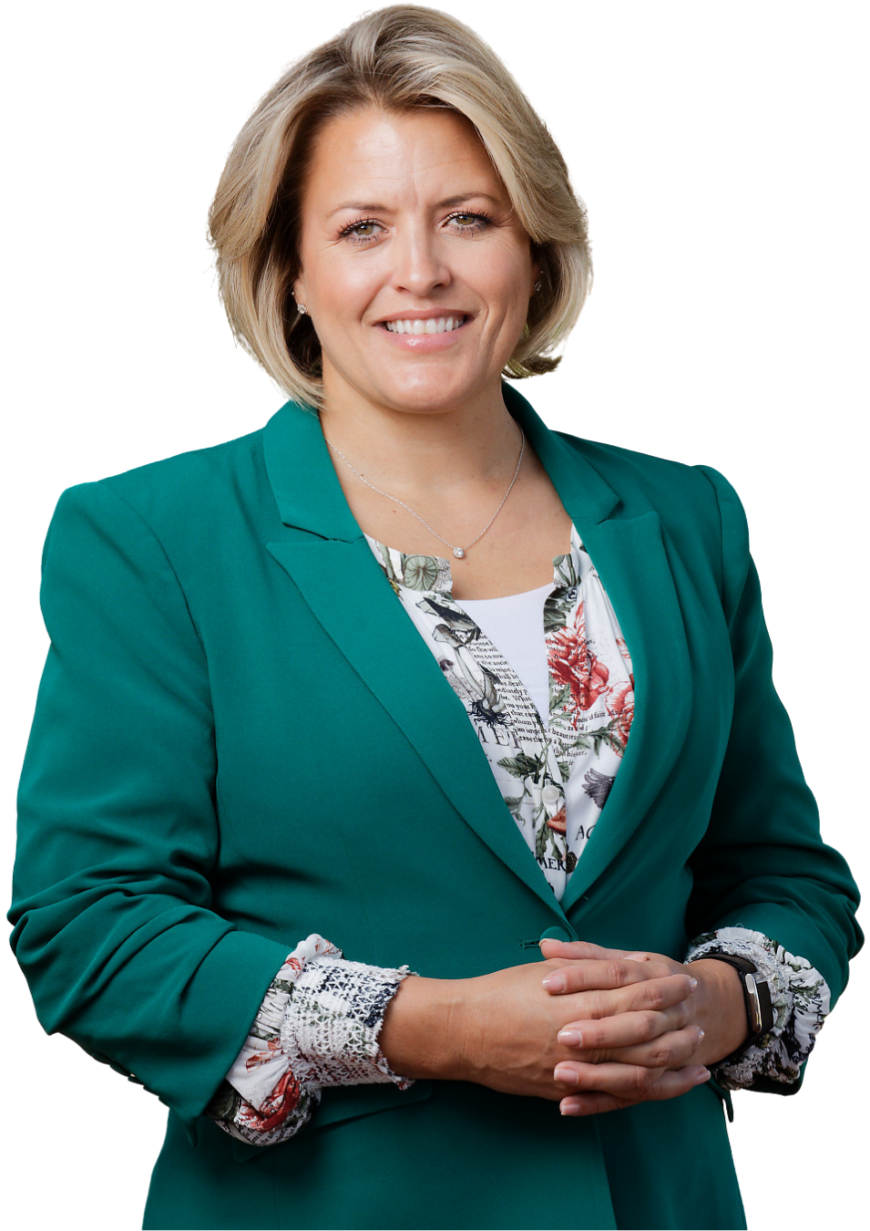Professional woman with short blonde hair smiling, wearing a green blazer over a floral blouse, with her hands clasped together.