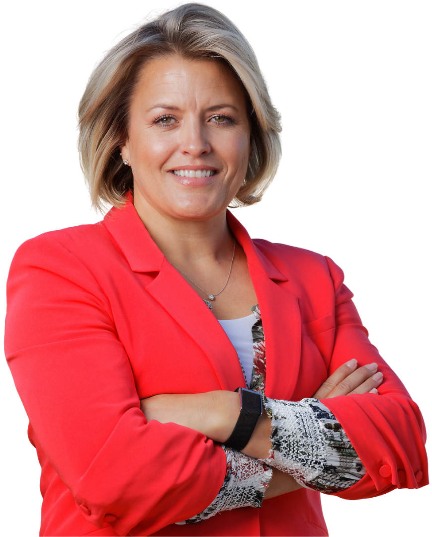 A confident middle-aged woman with shoulder-length blonde hair, wearing a red blazer over a patterned blouse, smiling with her arms crossed.