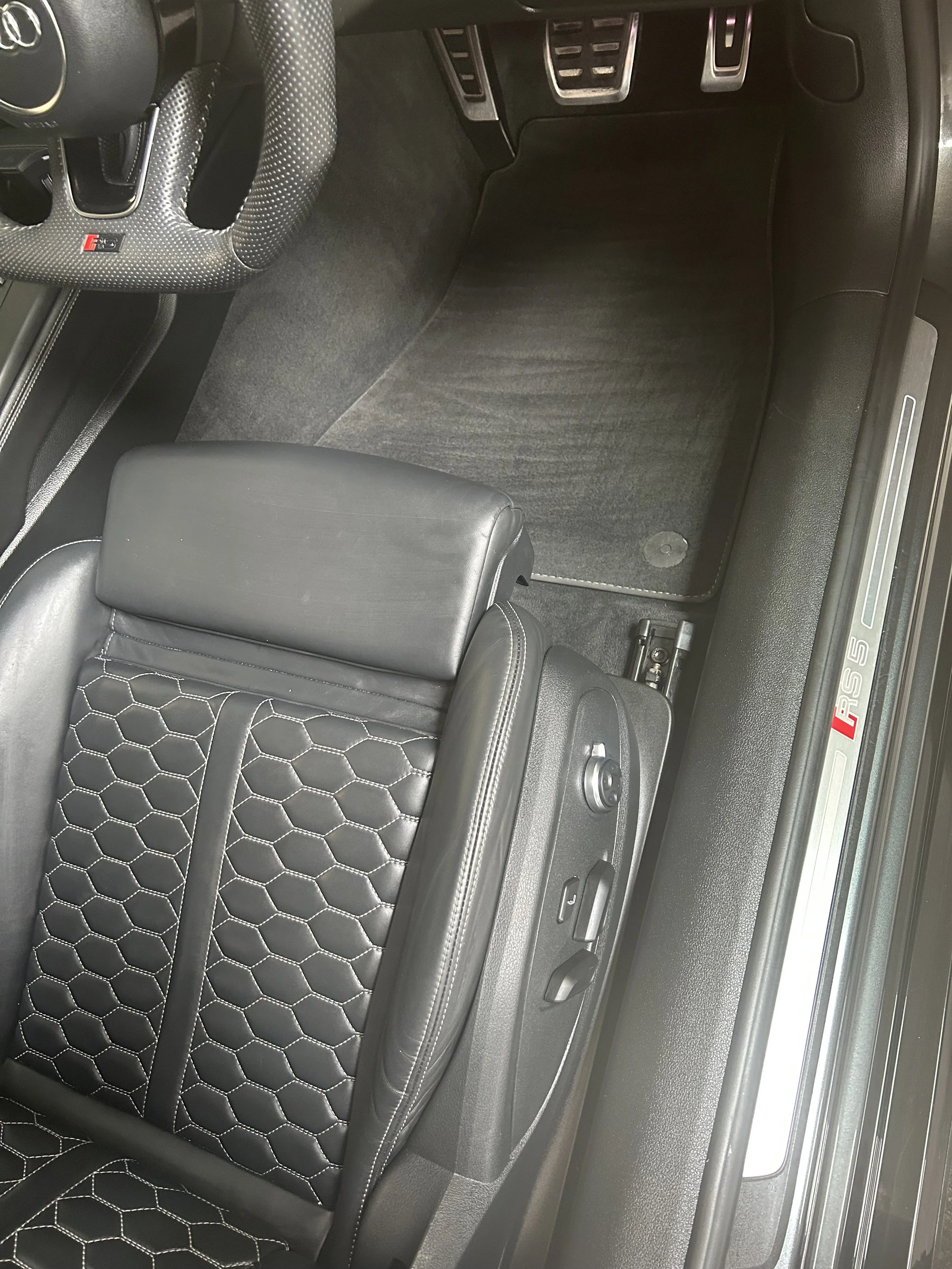 Luxury car interior after full interior detail, including cleaned driver’s seat, steering wheel, and floor mat.