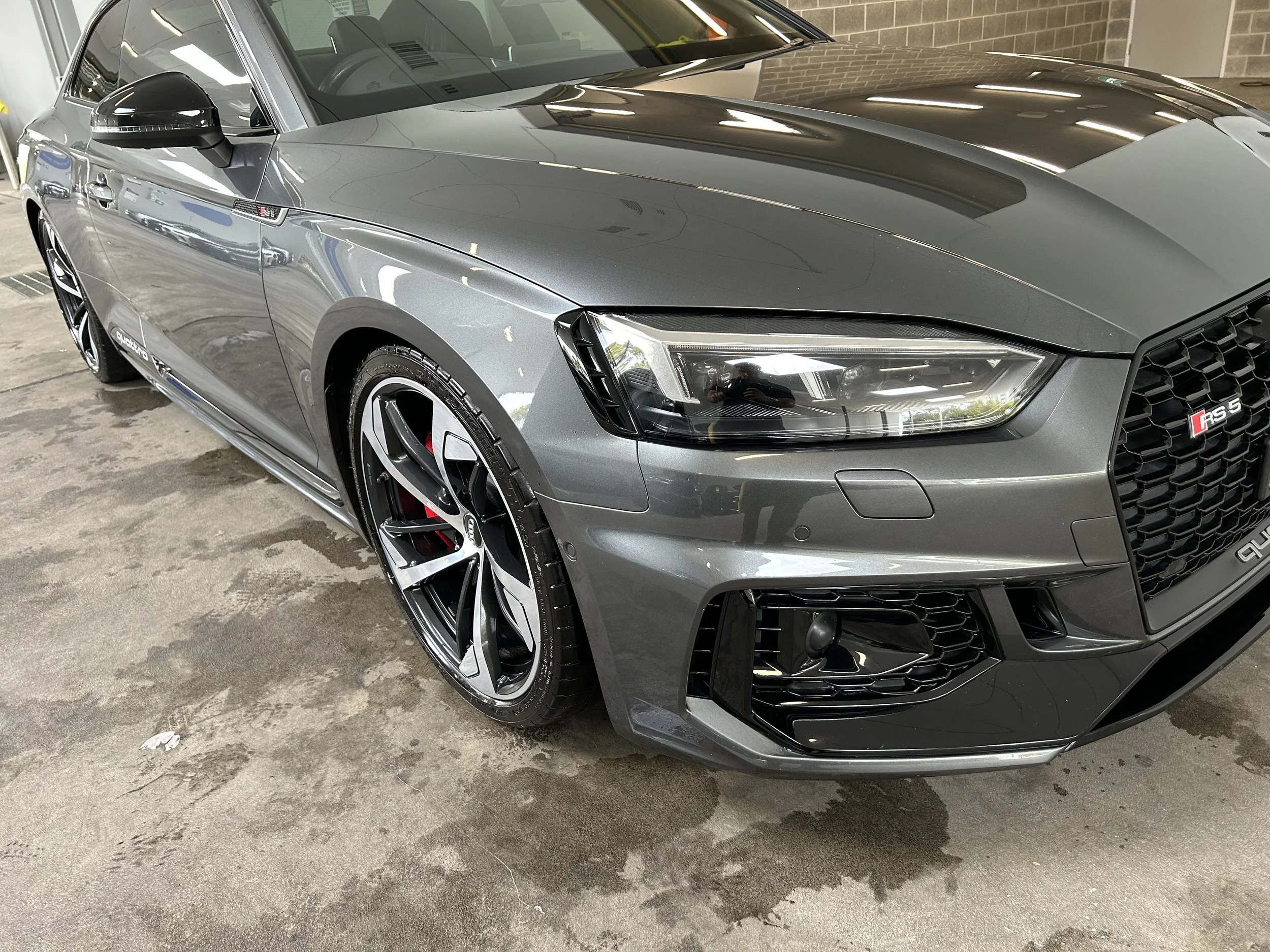 Front three-quarter view of a grey Audi RS5 after professional detailing, showing a glossy finish, restored paintwork, and a clean, polished exterior.