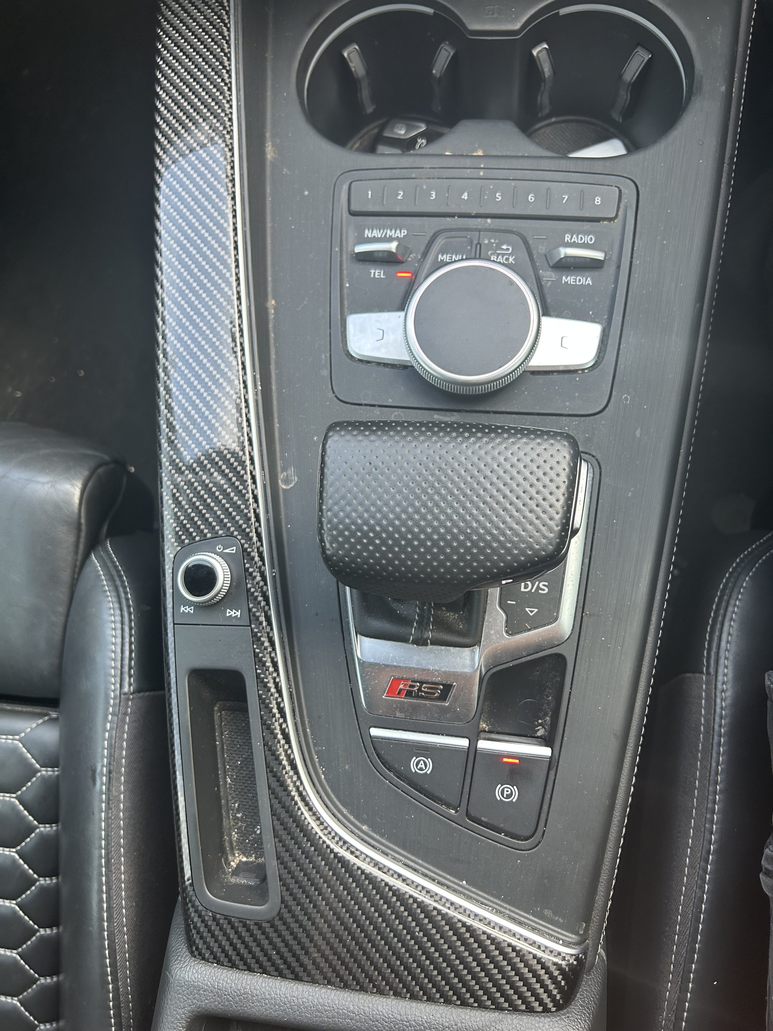 Before interior detail – center console showing dust, debris, and fingerprints on the controls, gear shift area, and carbon-fiber trim of an RS model vehicle.