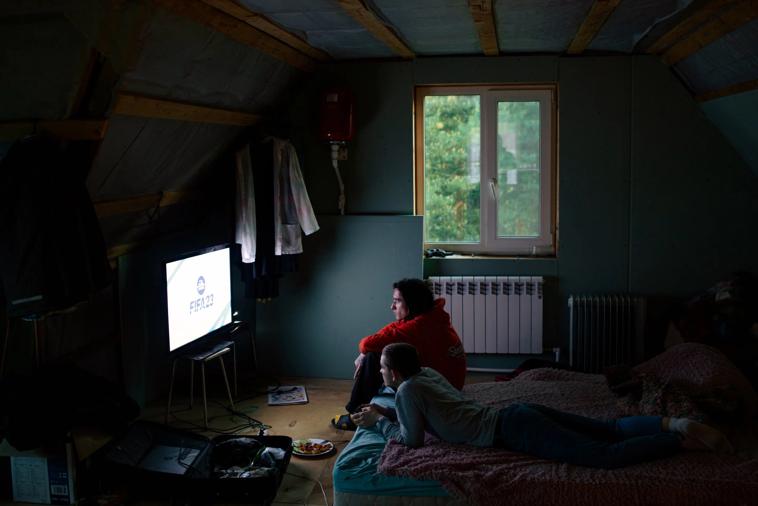 Teenagers watching television inside an attic bedroom in rural Russia. Photograph by Semyon Kokorin featured in “Semyon’s World” by Timofey Abel.