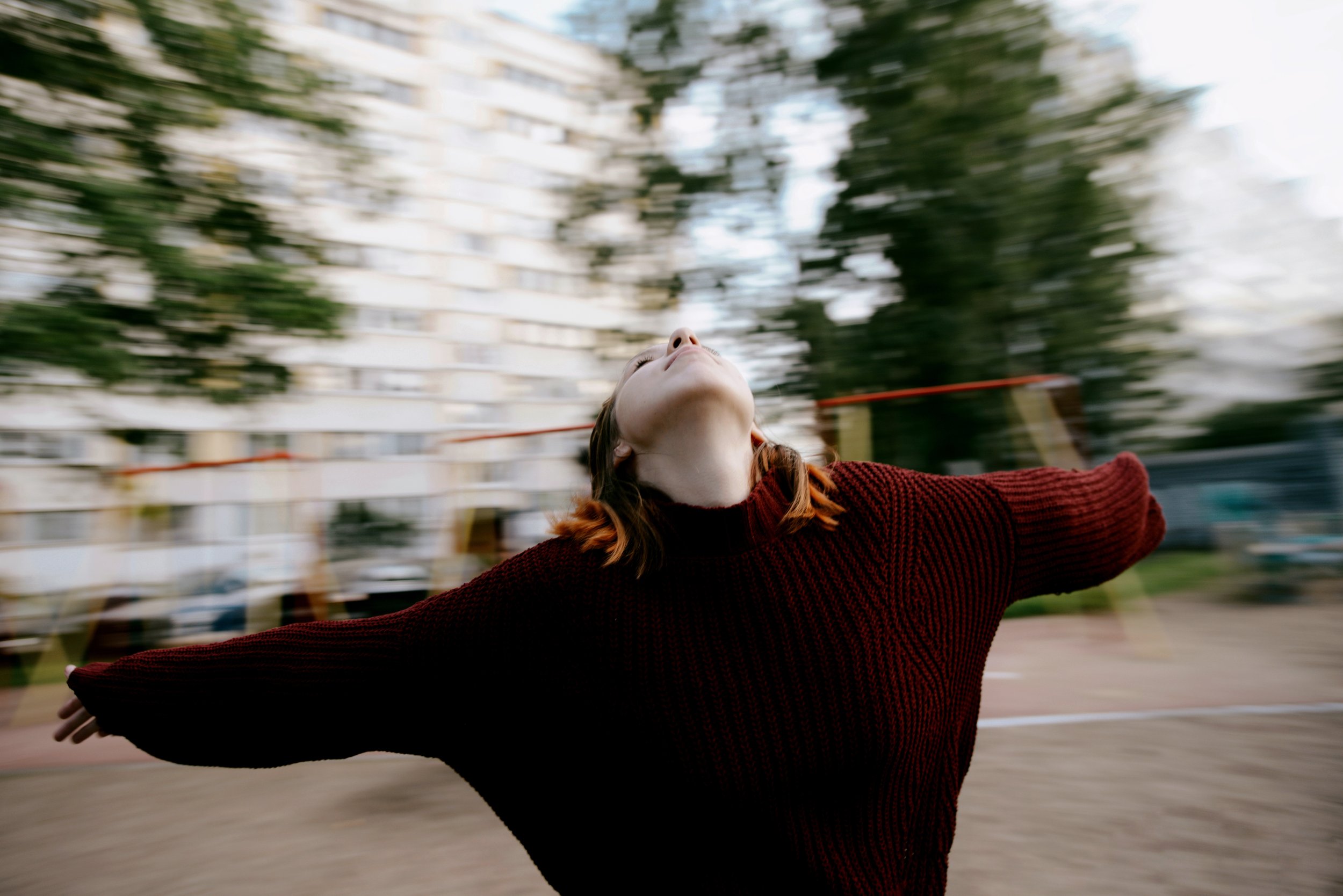 Young woman spinning with outstretched arms in a residential courtyard in post-Soviet Russia. Photograph by Semyon Kokorin featured in “Semyon’s World” by Timofey Abel.