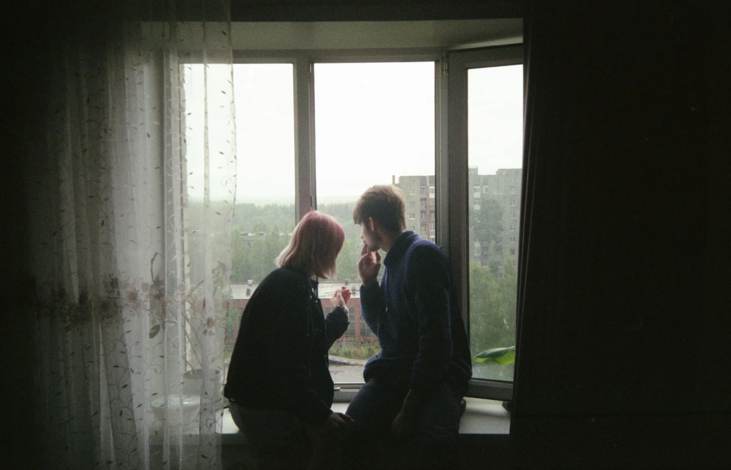 Two teenagers sitting by an apartment window during lockdown in post-Soviet Russia. Photograph by Semyon Kokorin featured in “Semyon’s World” by Timofey Abel.